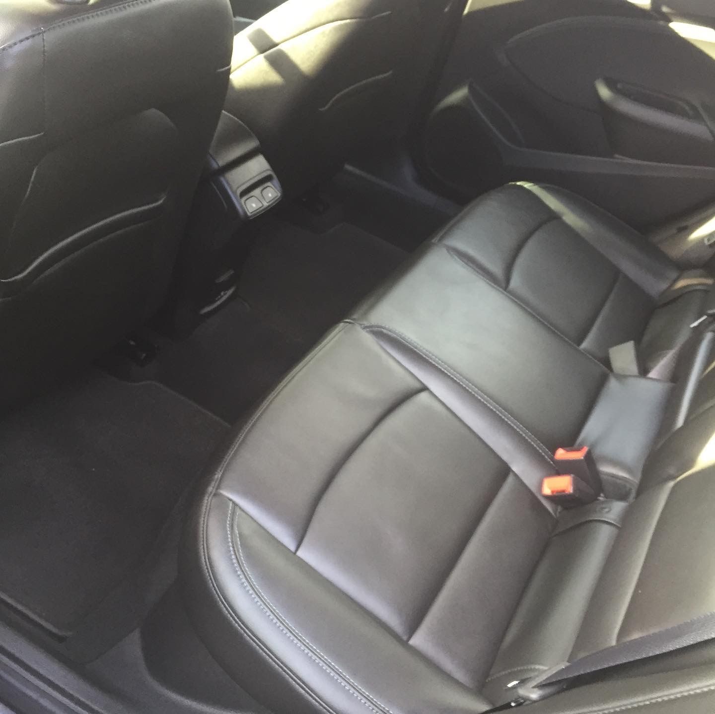 The back seat of a car with black leather seats