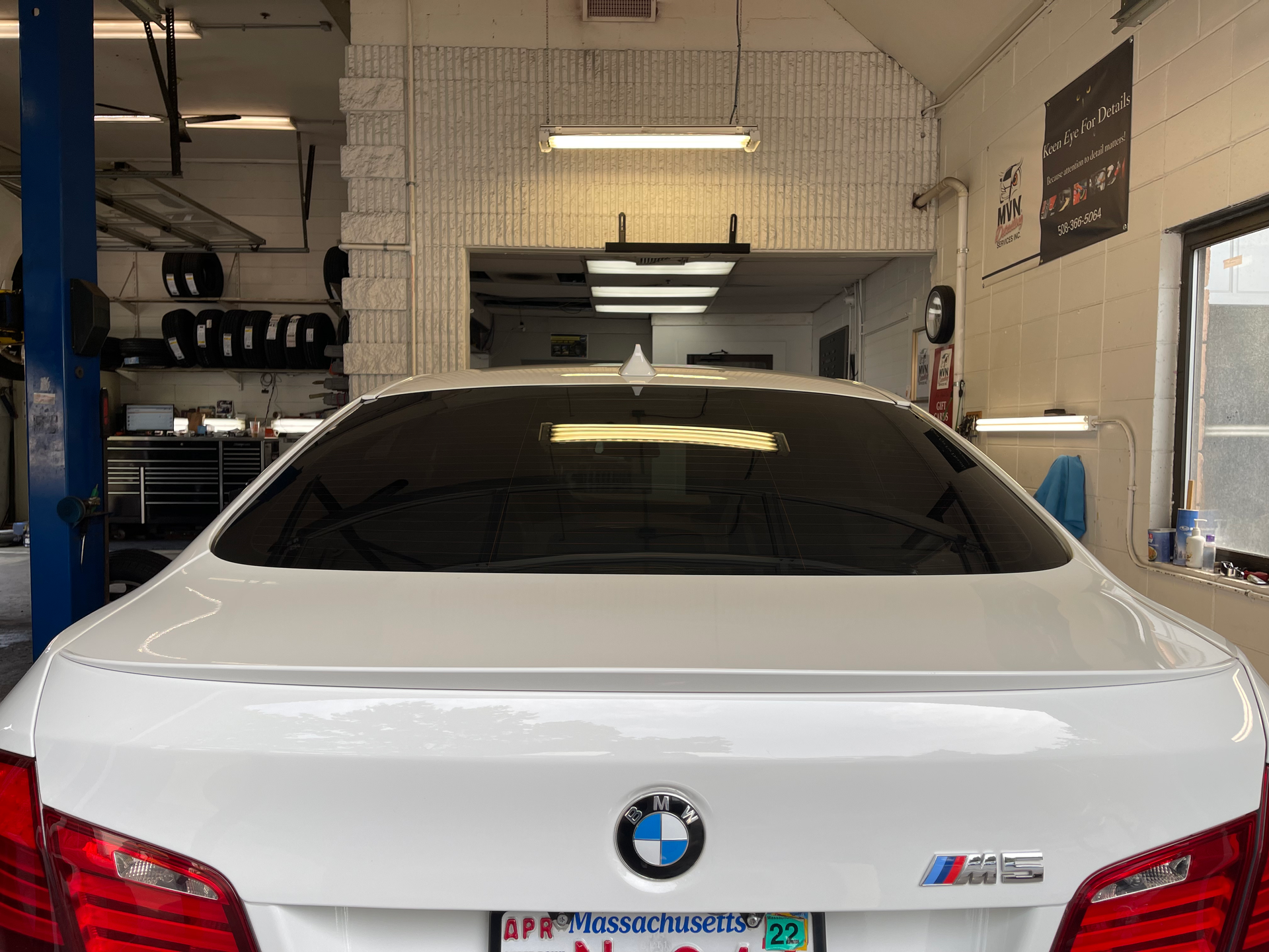 A white bmw is parked in a garage on a lift.