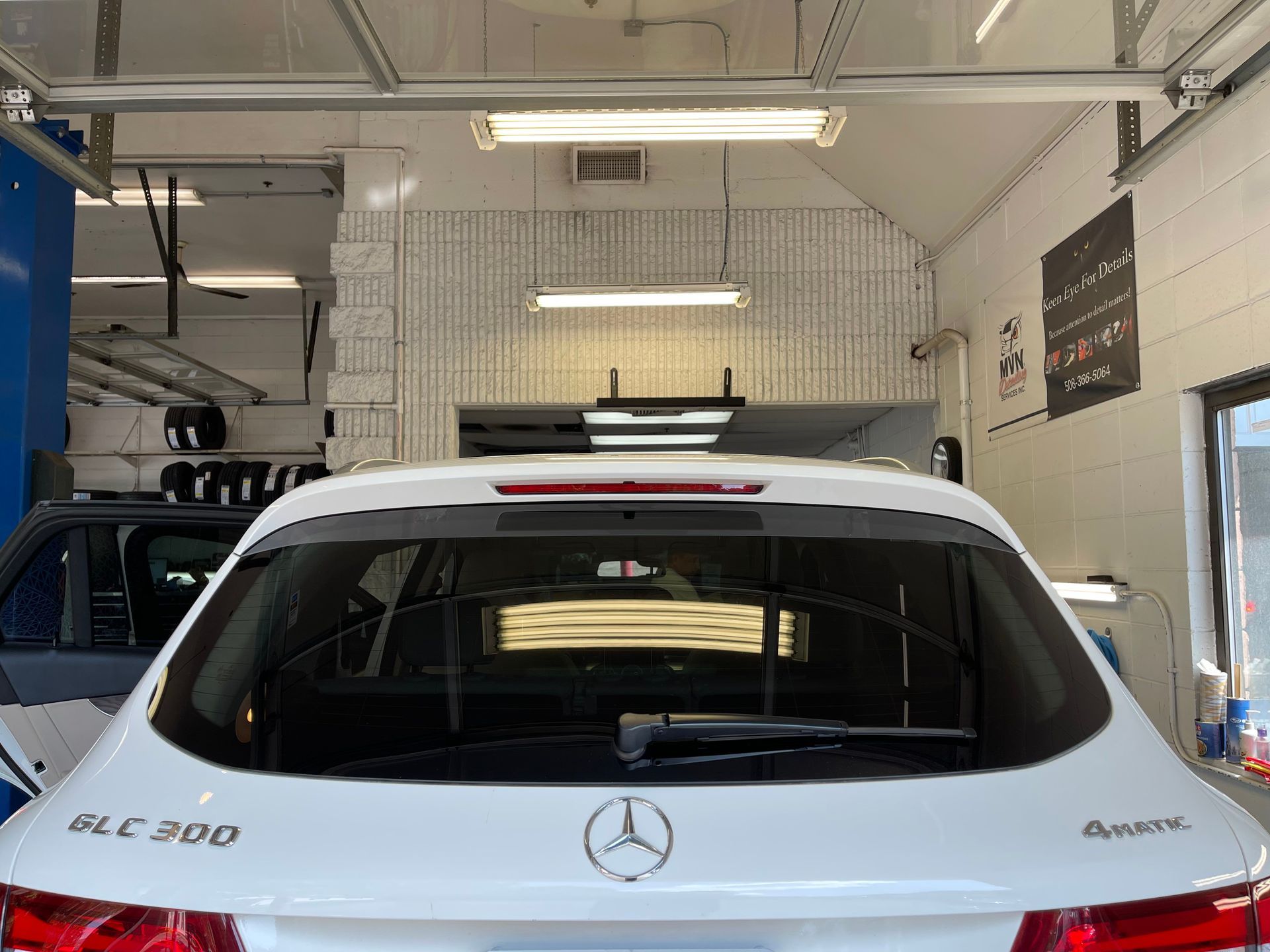 A white mercedes benz glc 200 is parked in a garage.