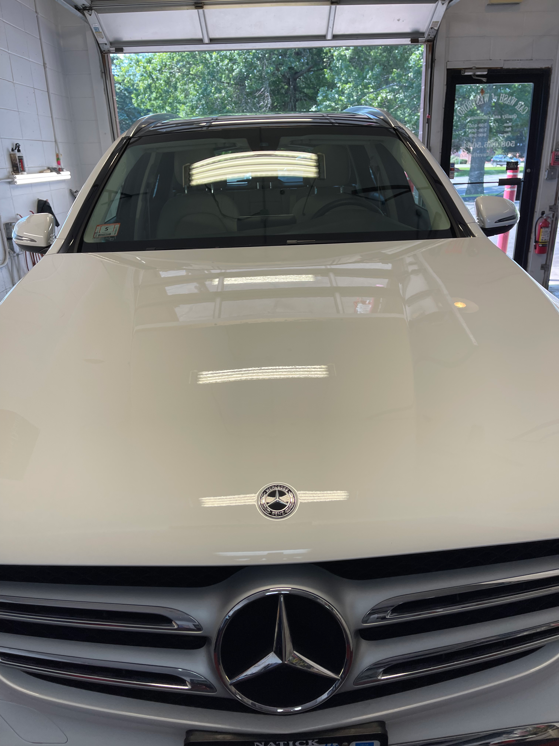 A white mercedes benz is parked in a garage.