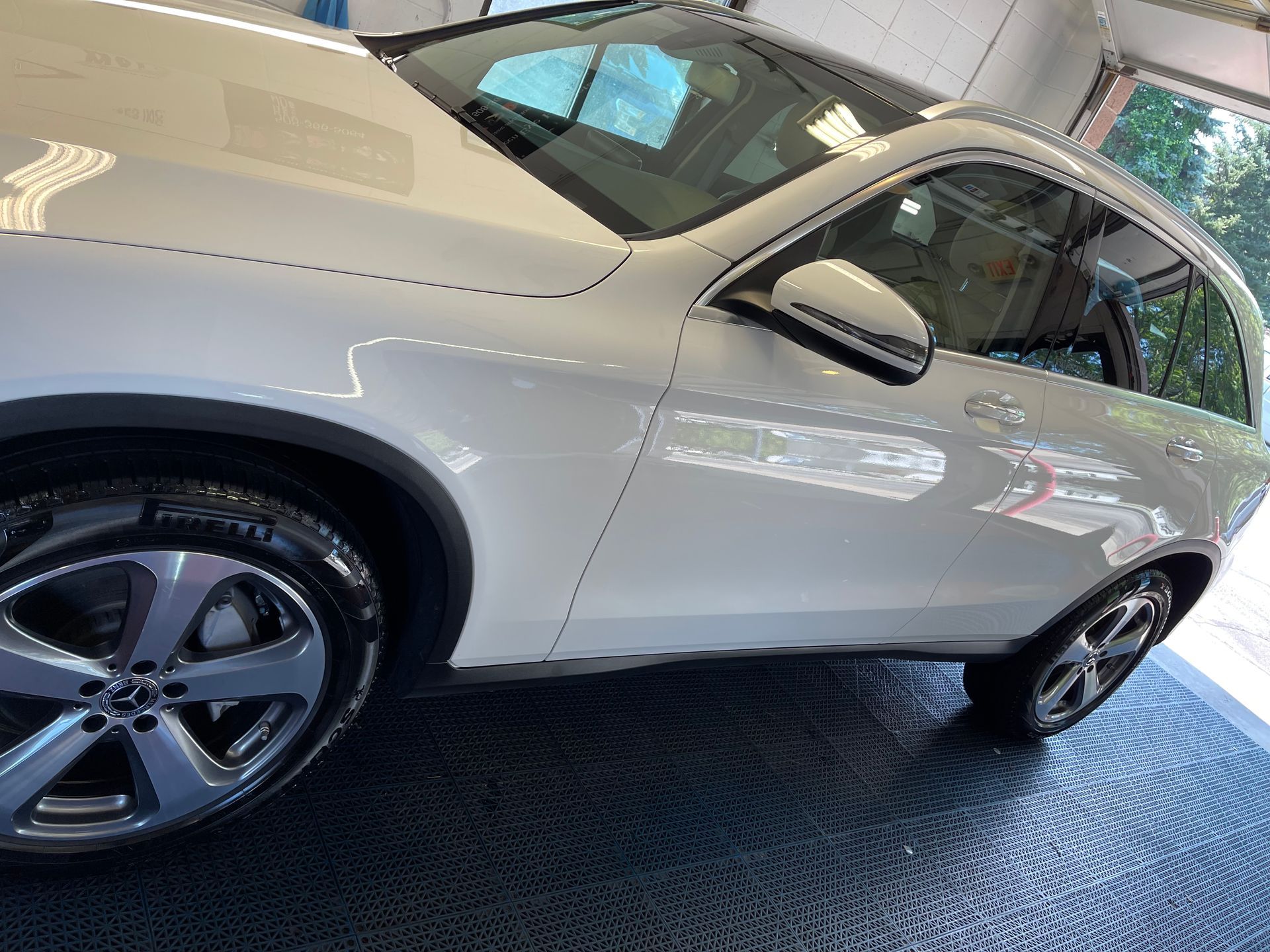 A white mercedes benz glc is parked in a garage.