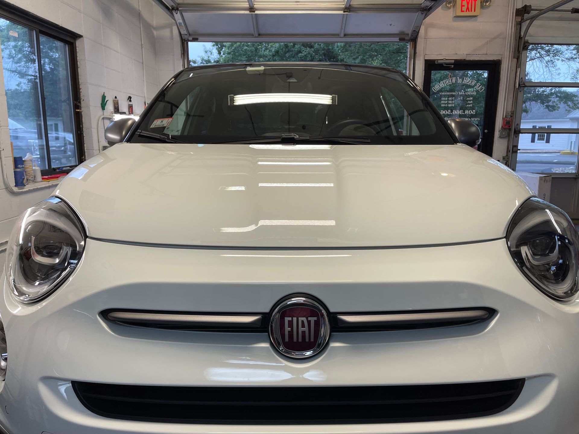A white fiat 500 is parked in a garage.