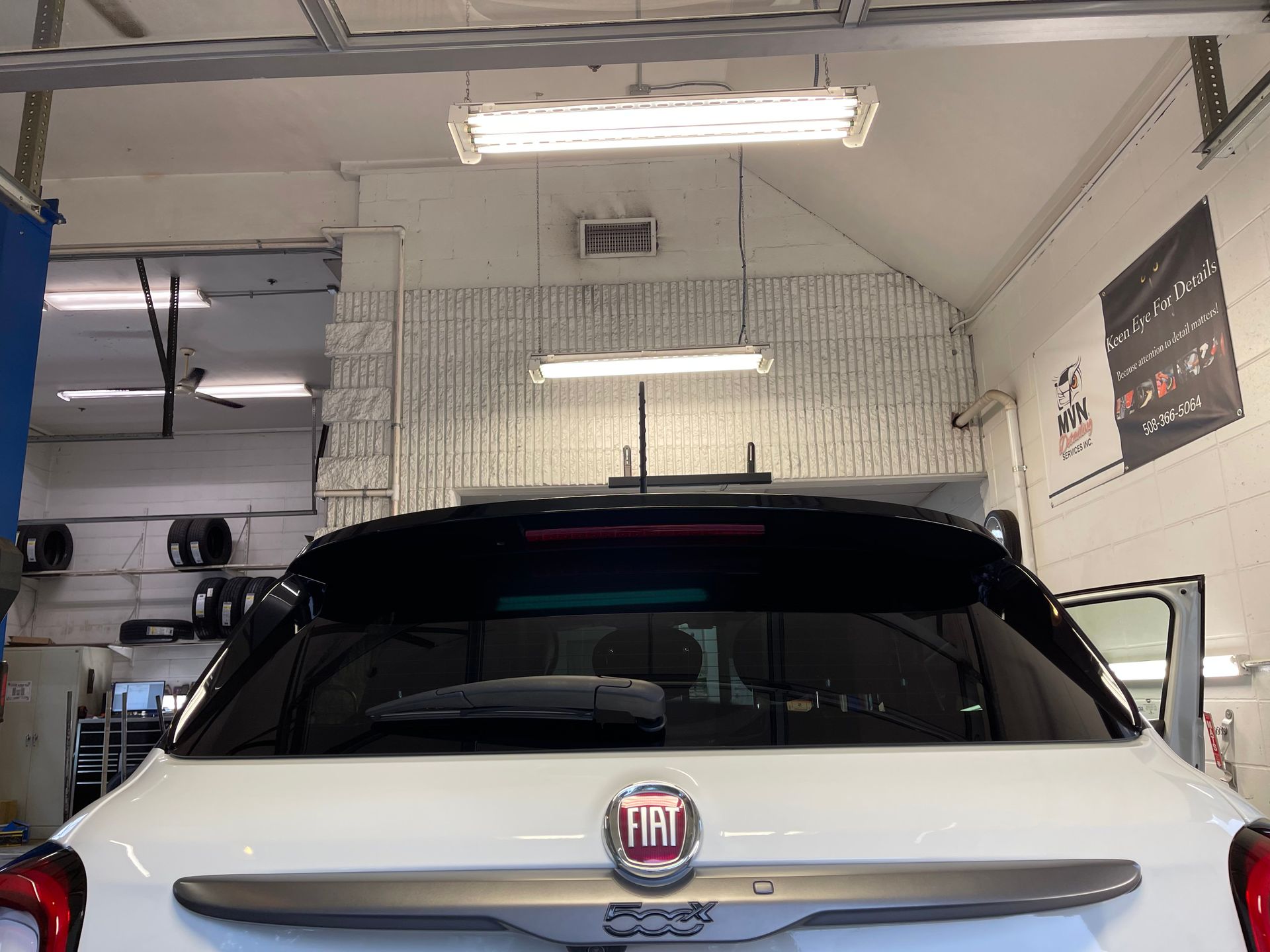 A white fiat 500 is parked in a garage.
