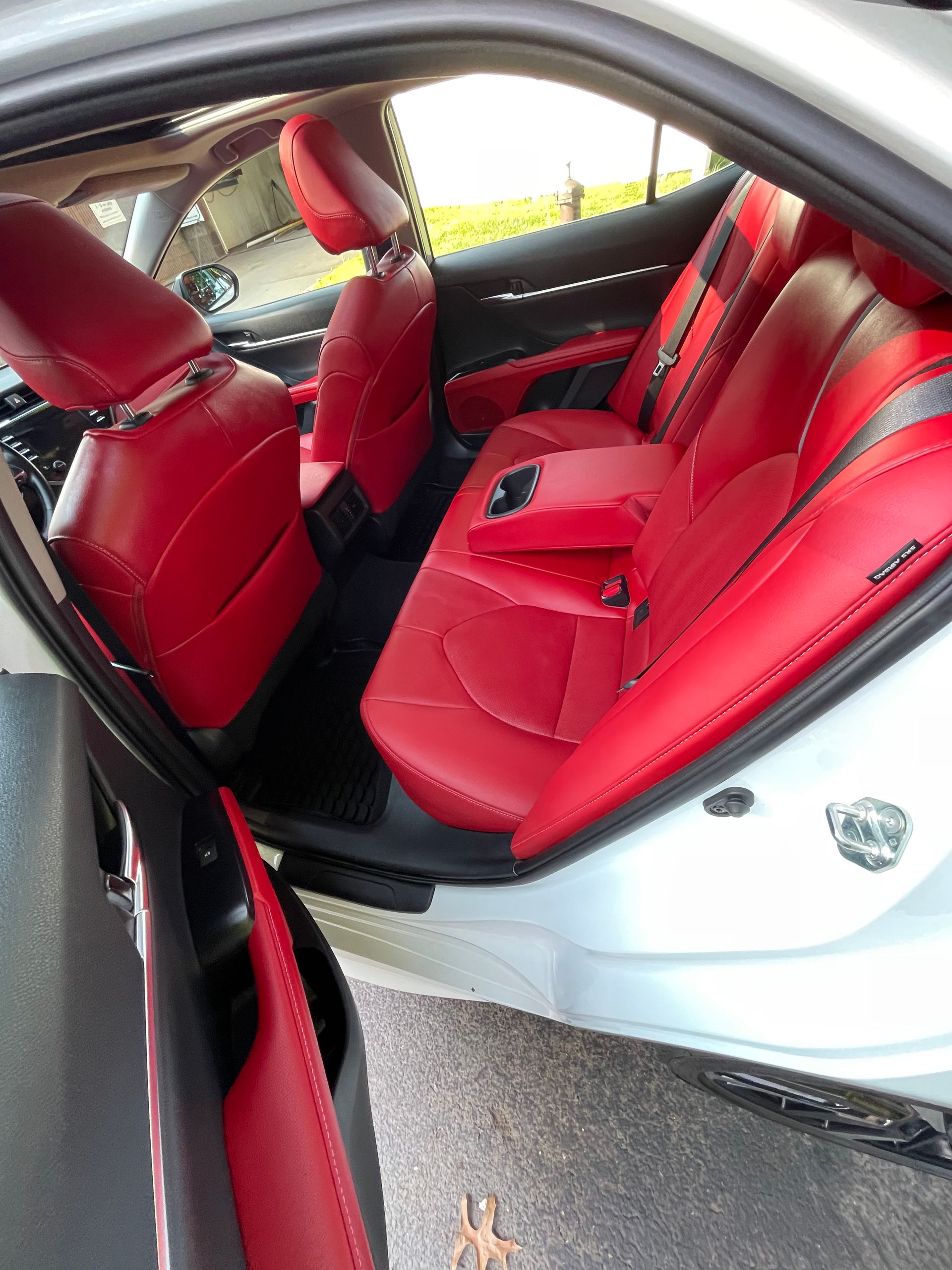 The back seat of a white car with red seats
