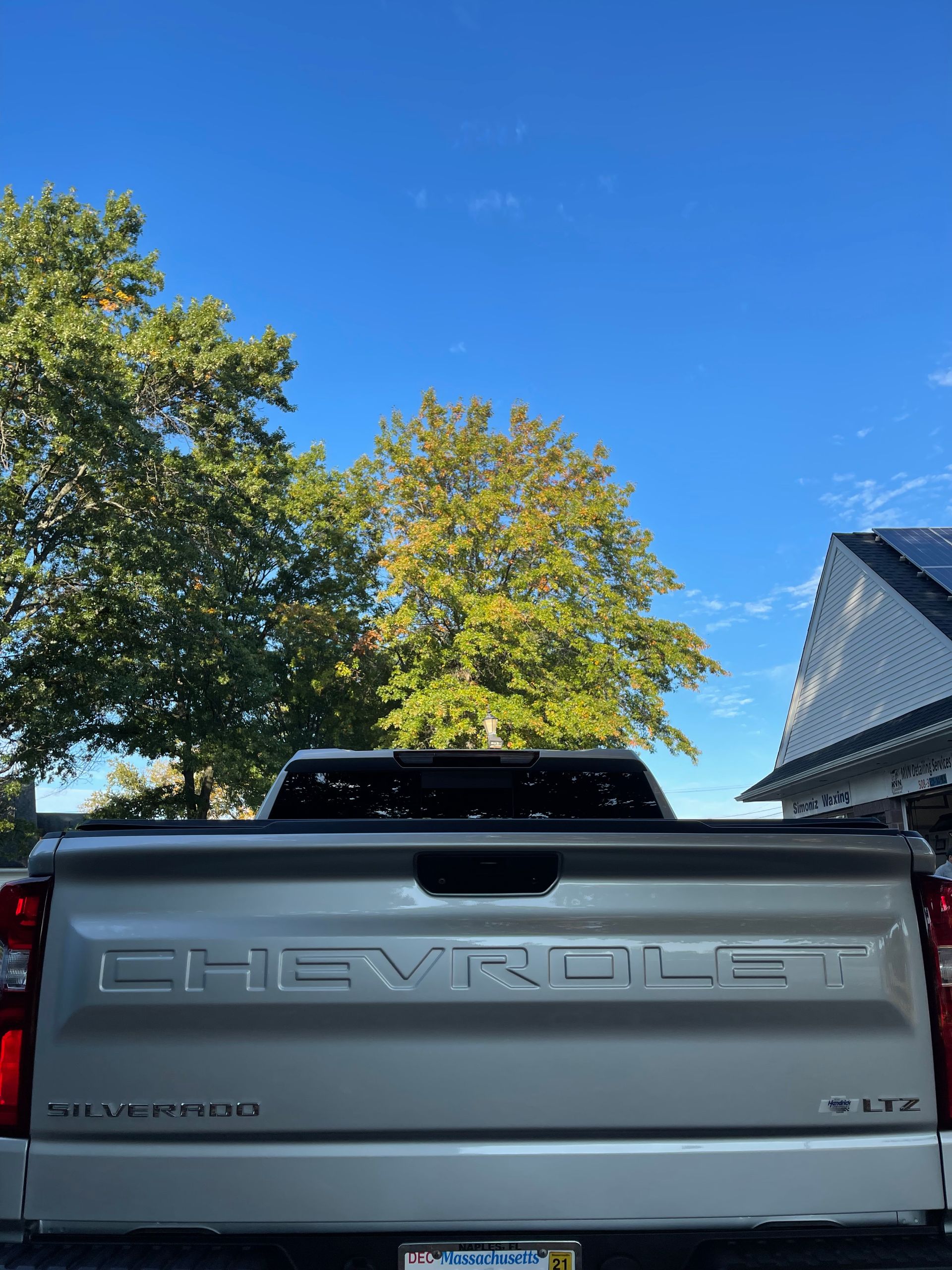 A silver chevrolet truck is parked in front of a house.