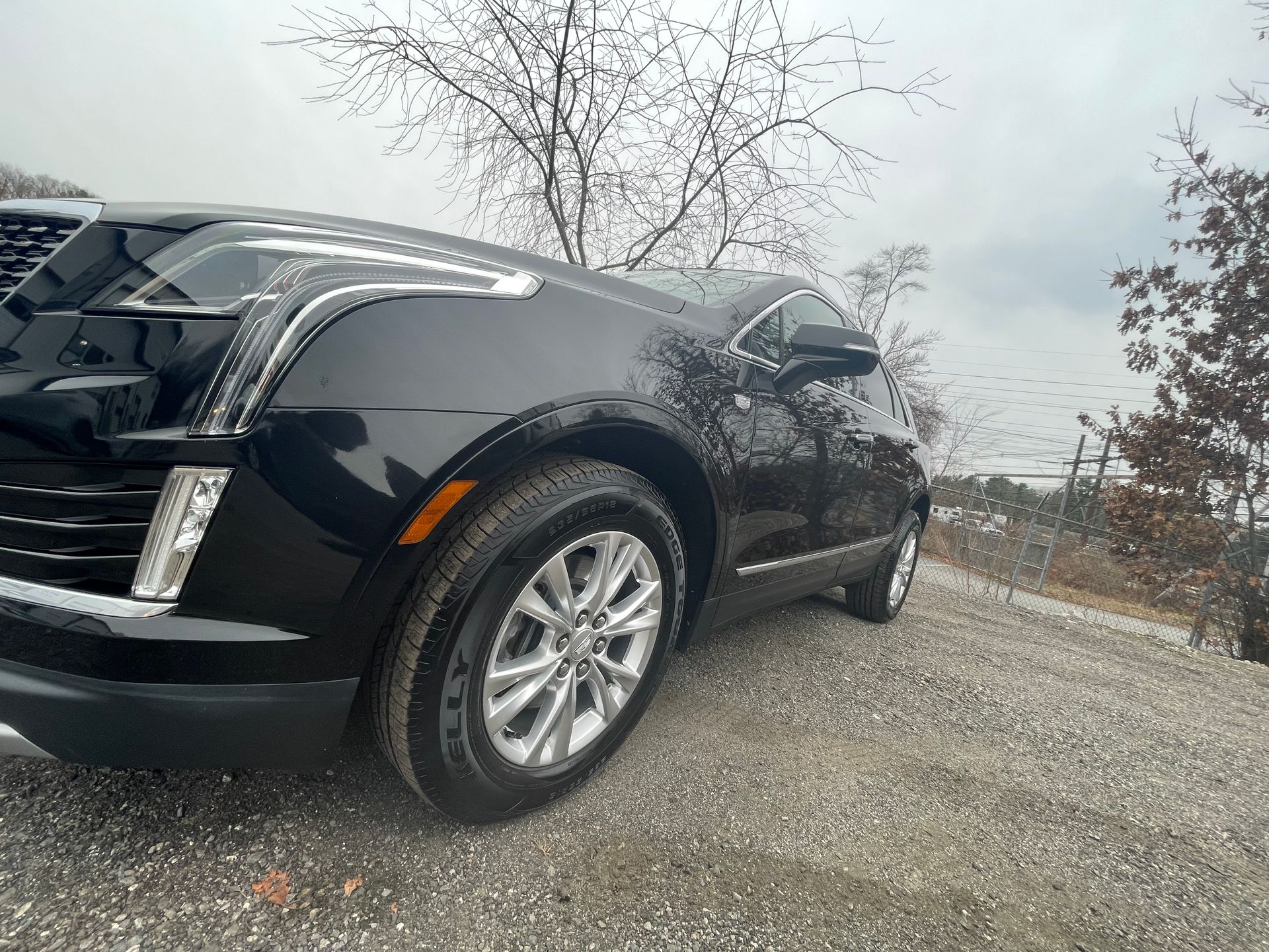 A black car is parked on a gravel road.