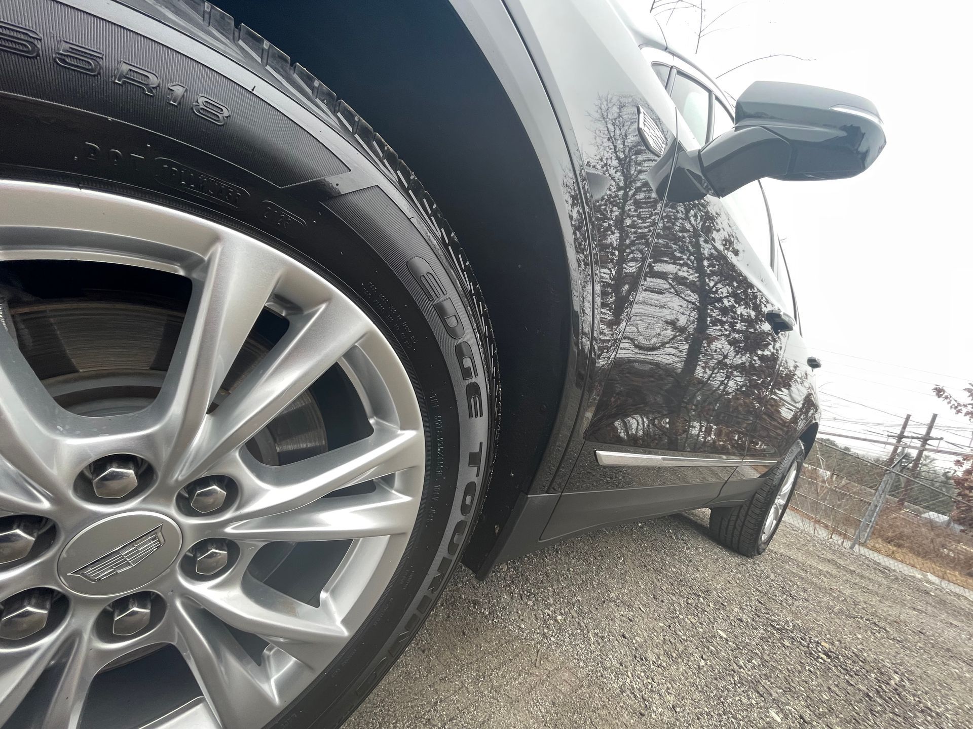 A close up of a car tire on a gravel road.