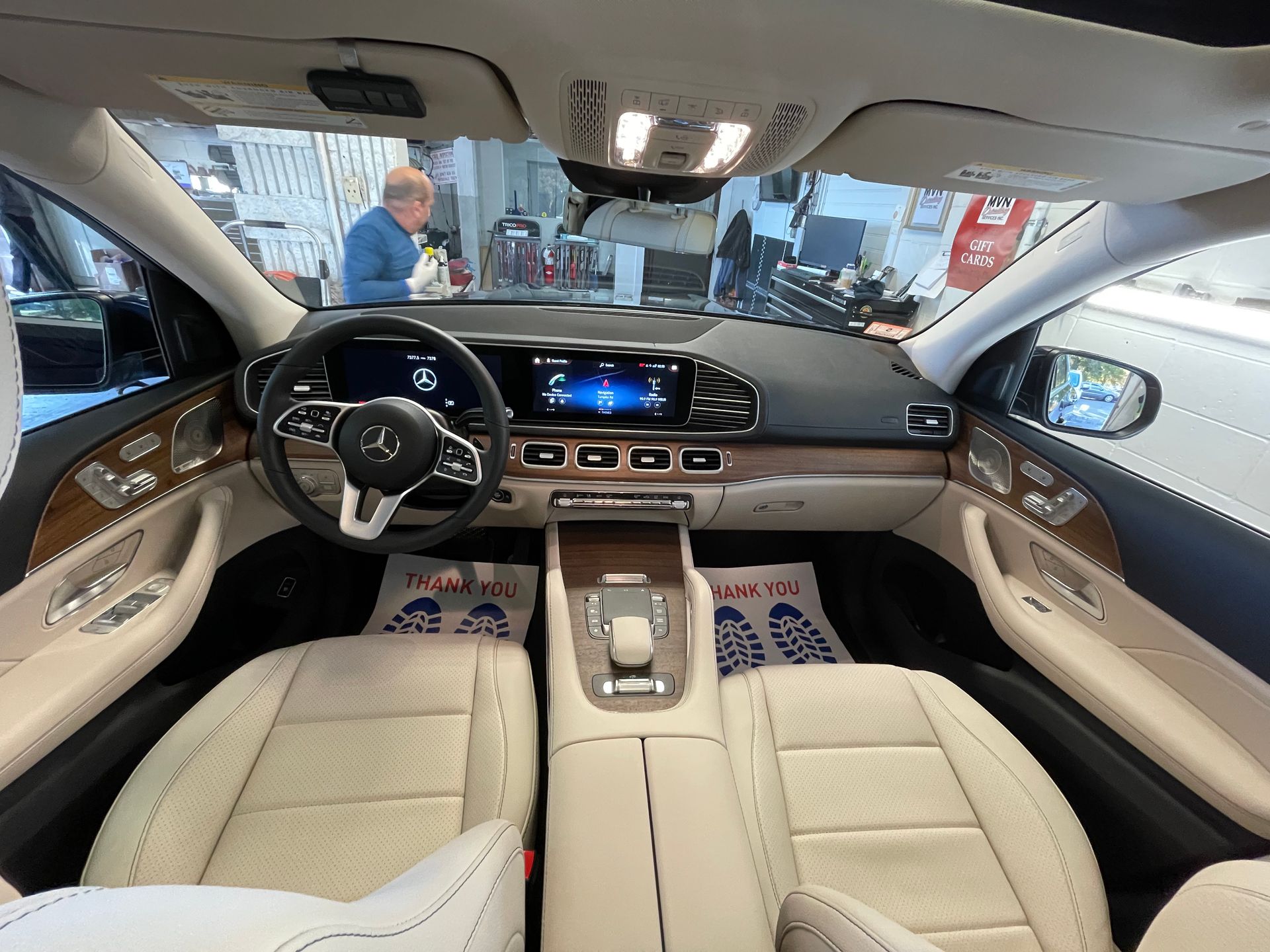 The inside of a car with a man standing in the background.