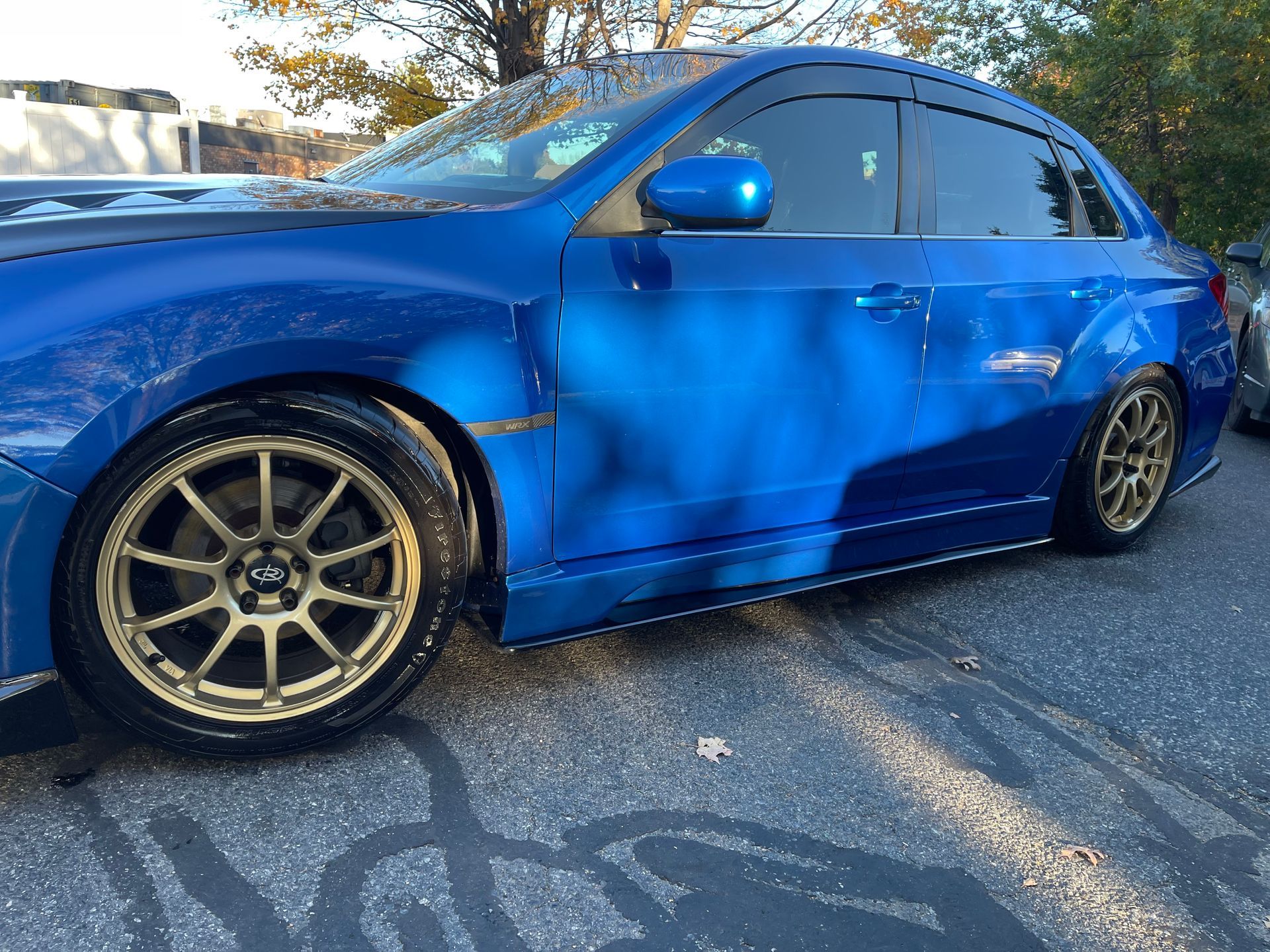 A blue car with gold wheels is parked on the side of the road