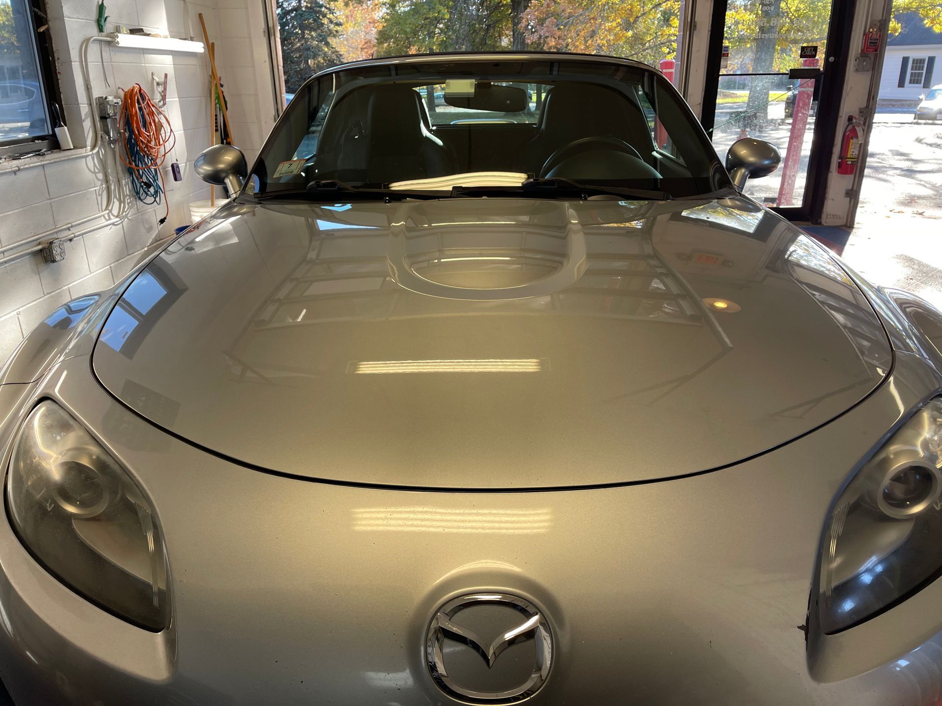 A silver mazda sports car is parked in a garage.