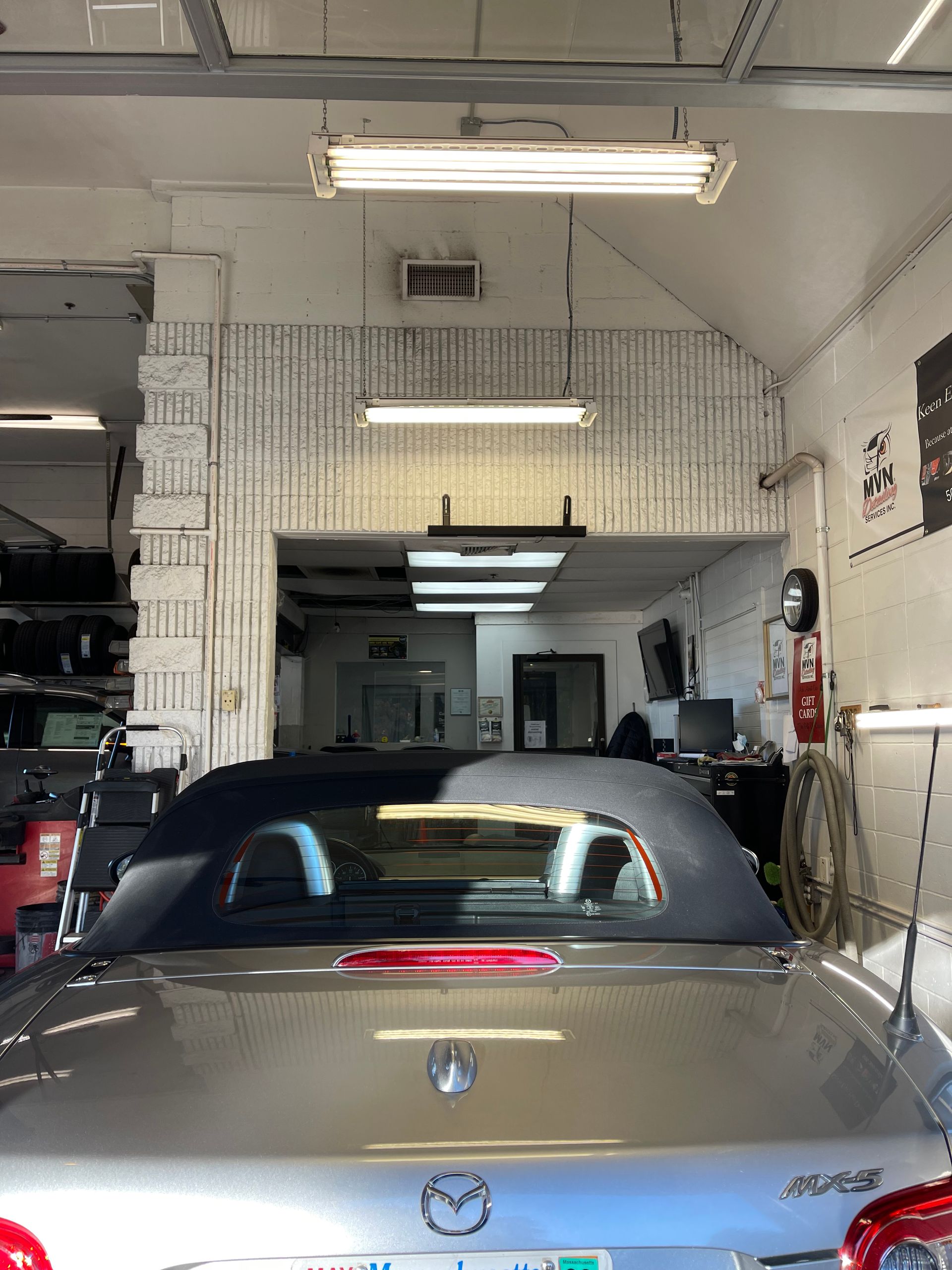 A silver convertible car is parked in a garage.