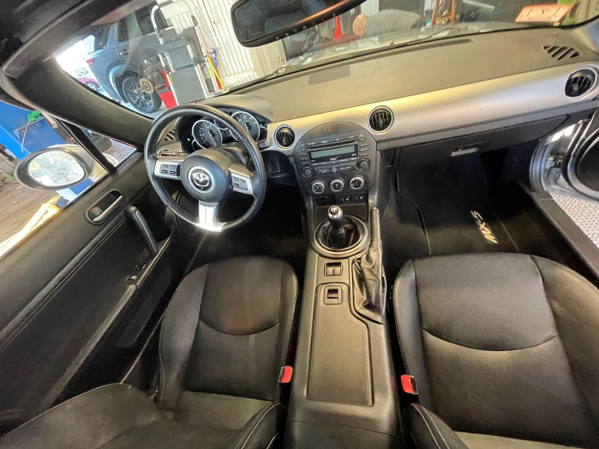 The interior of a black sports car with a steering wheel and seats.