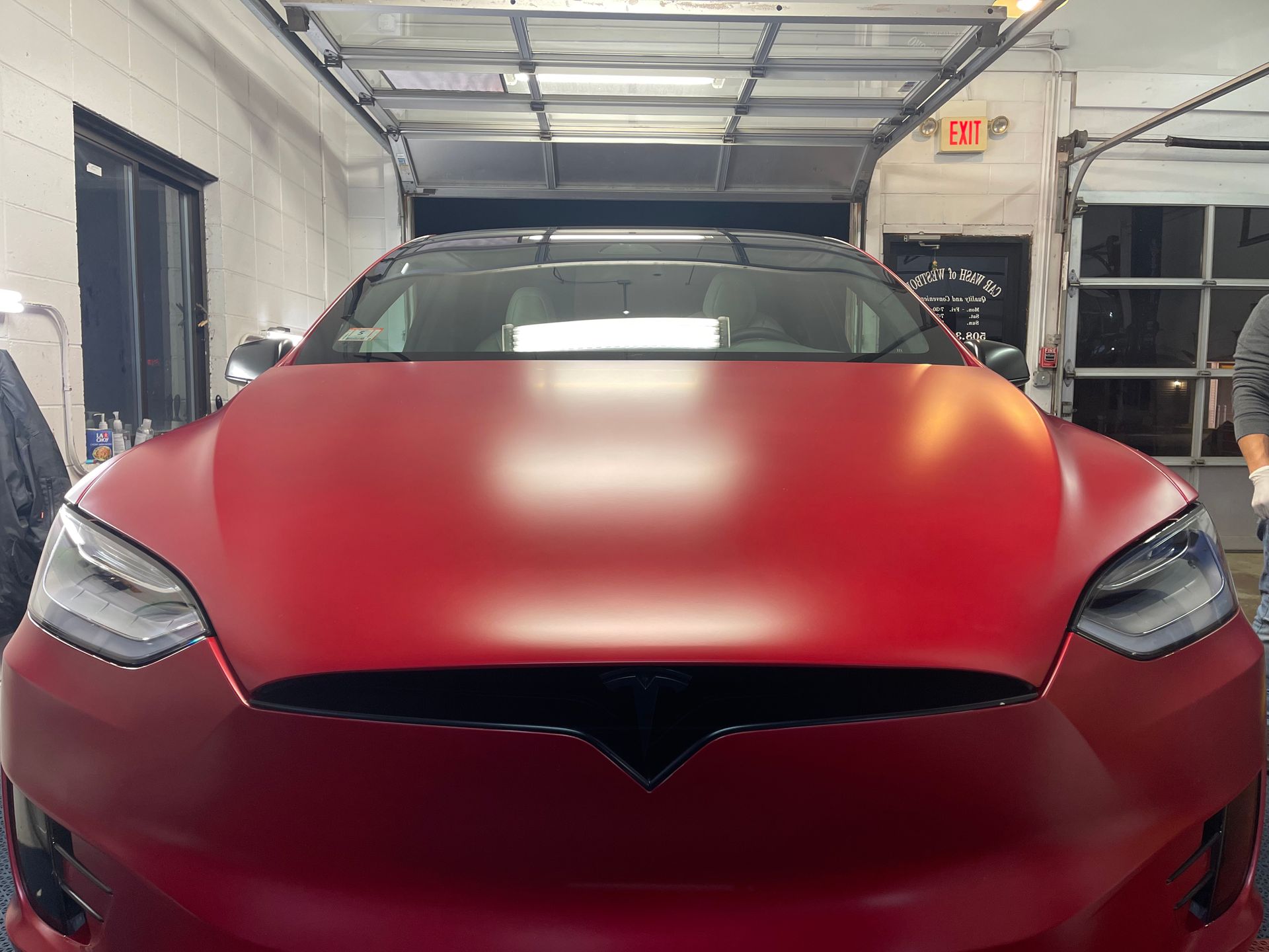 A red tesla model s is parked in a garage.