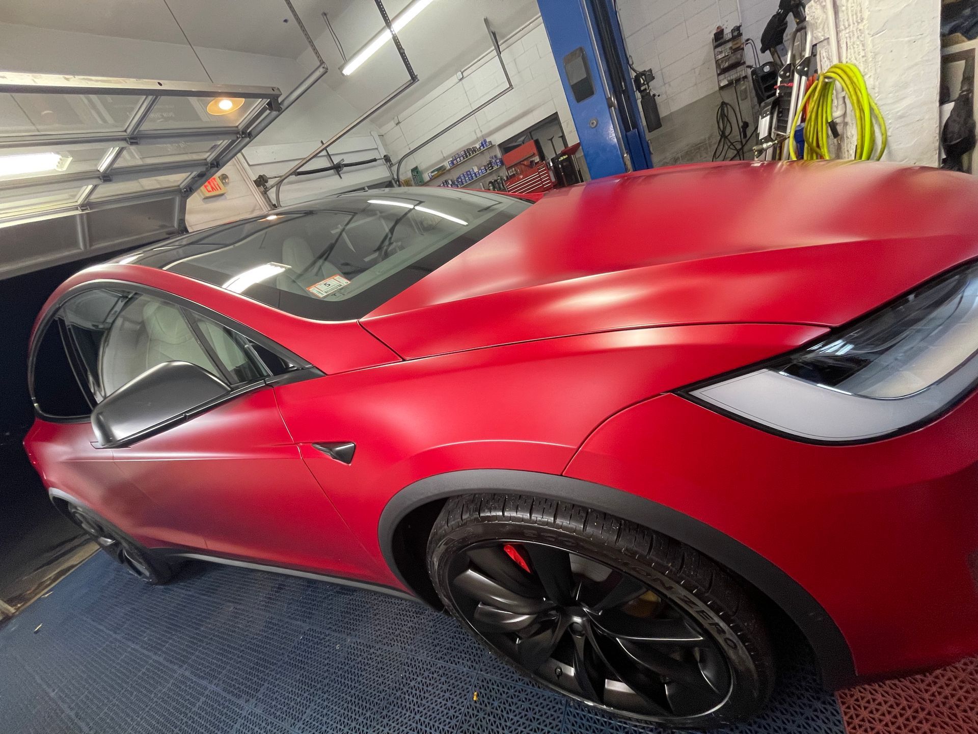 A red tesla model x is parked in a garage.