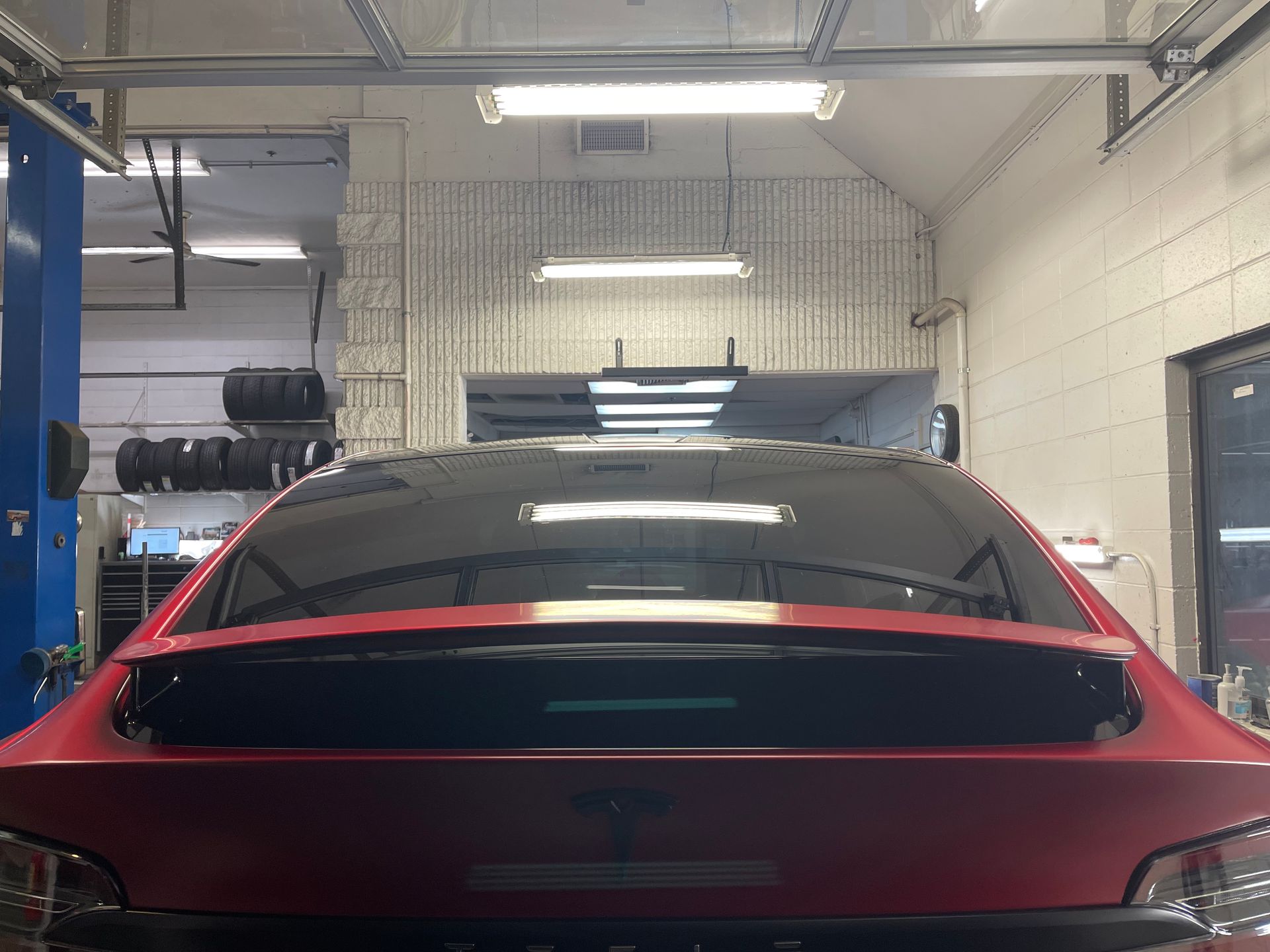 A red car is parked in a garage with a black roof.