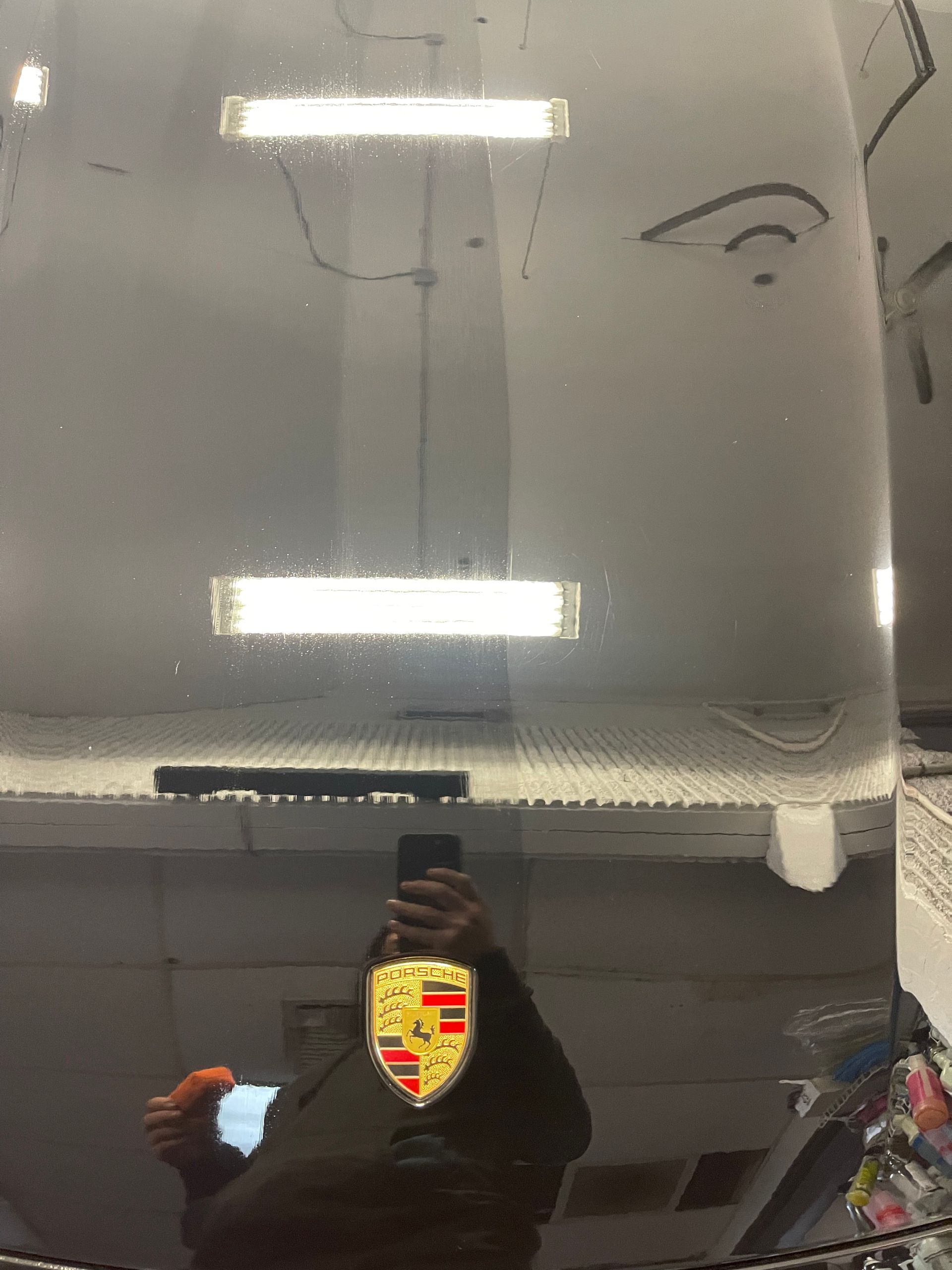 A person is taking a picture of their reflection in the windshield of a car.