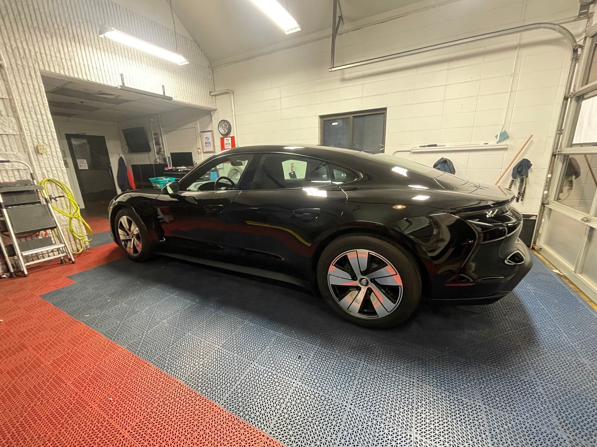 A black porsche taycan is parked in a garage.