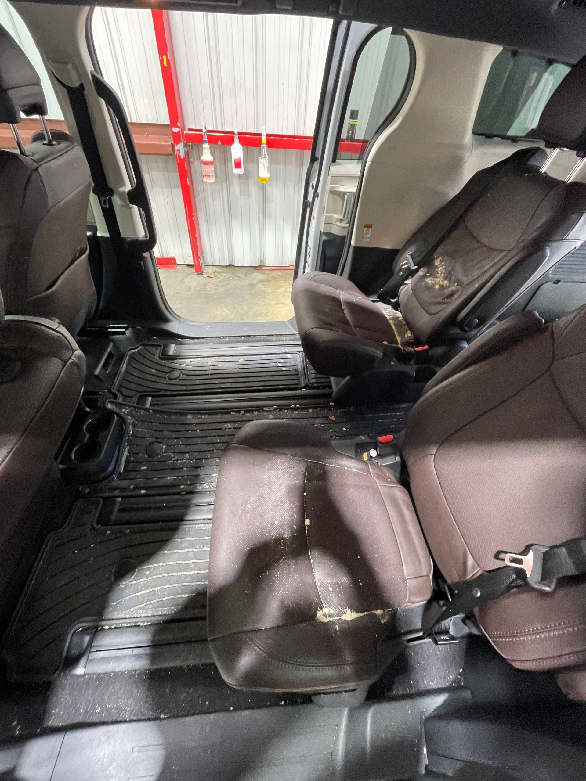 The rear seats of a minivan are empty and dirty.