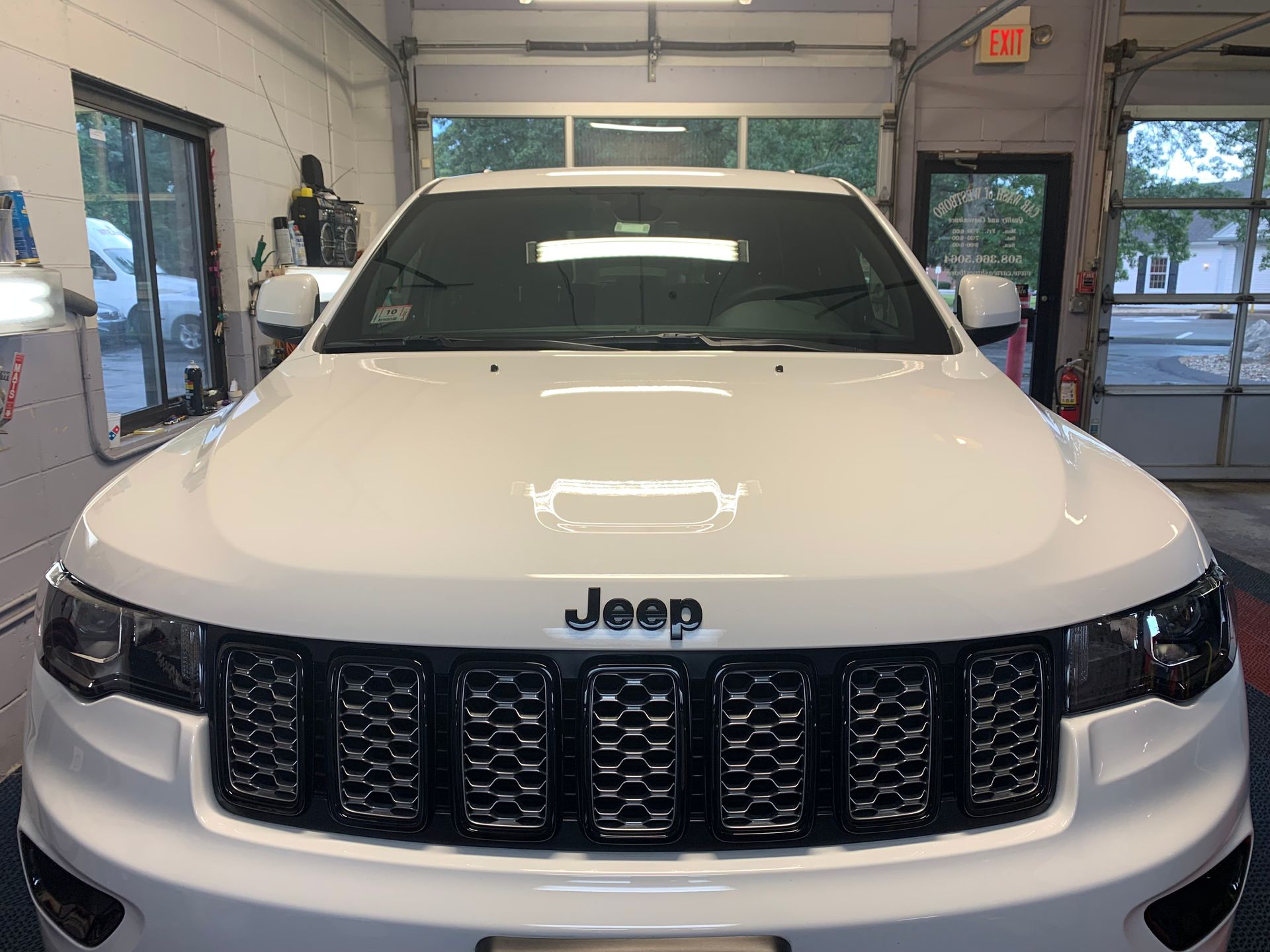 A white jeep is parked in a garage.