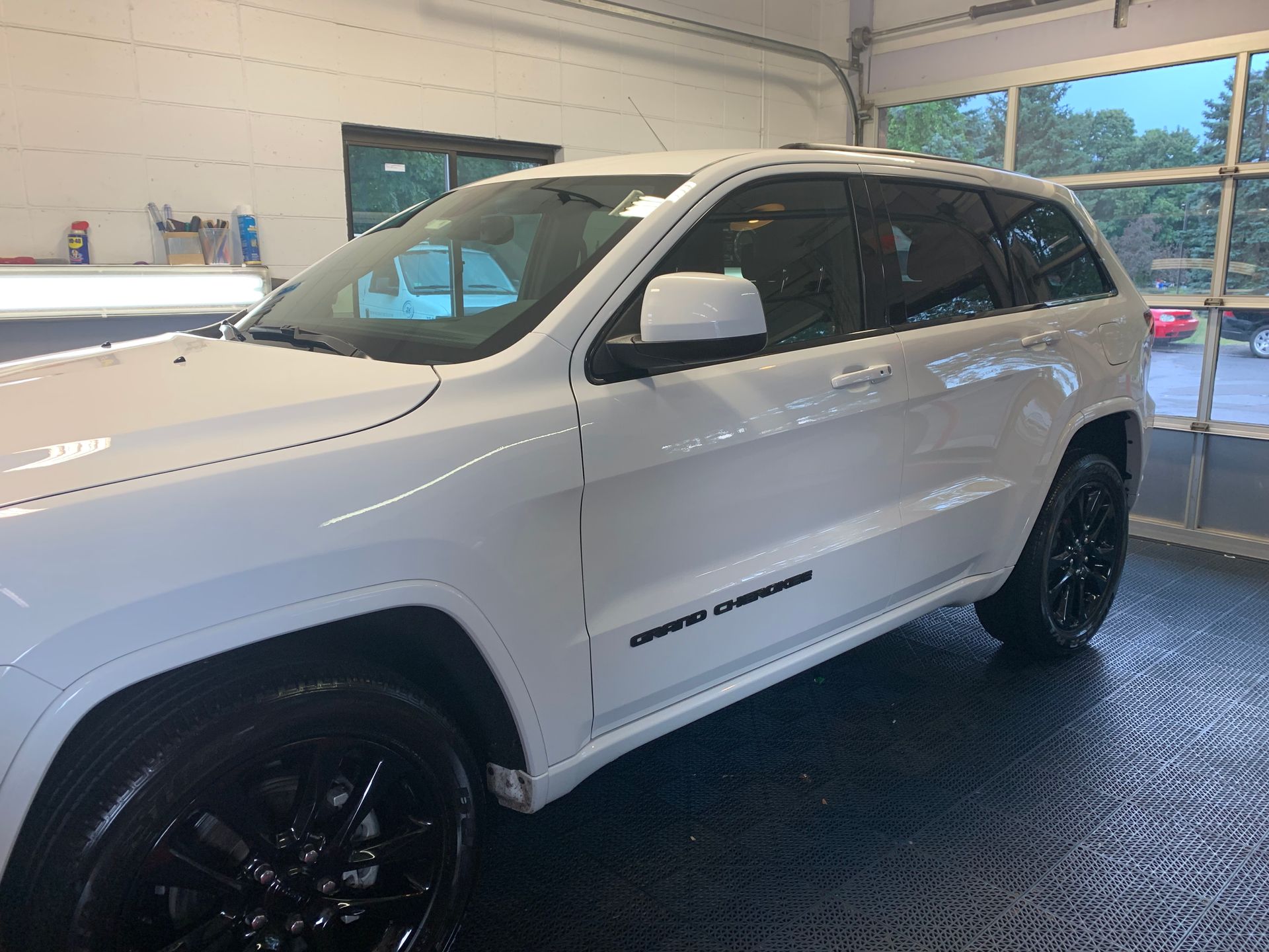 A white jeep grand cherokee is parked in a garage.