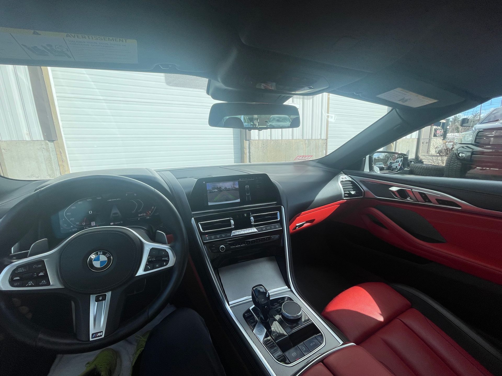 The interior of a bmw 8 series convertible with red seats and a steering wheel.