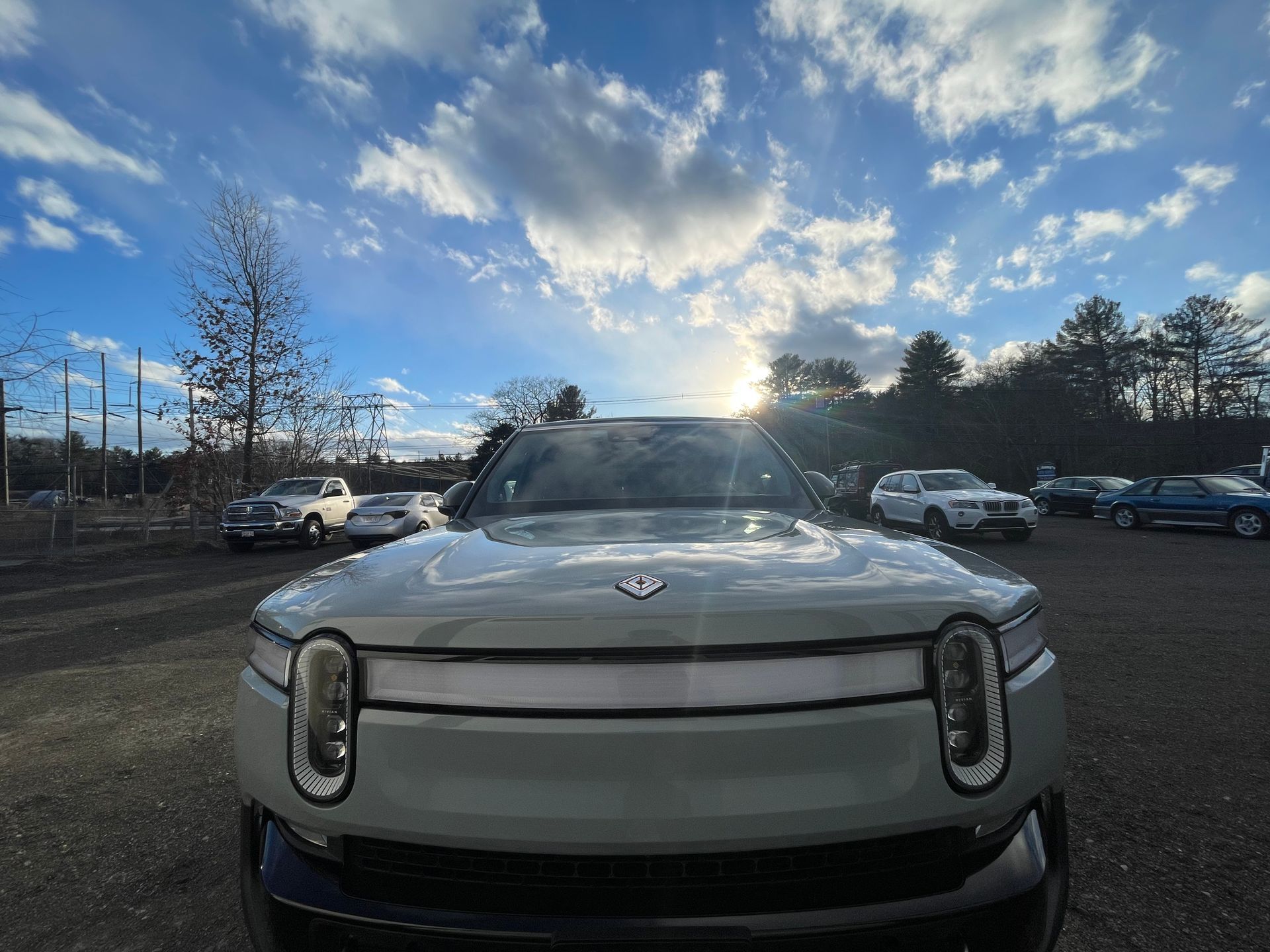 A white car is parked in a parking lot with other cars.
