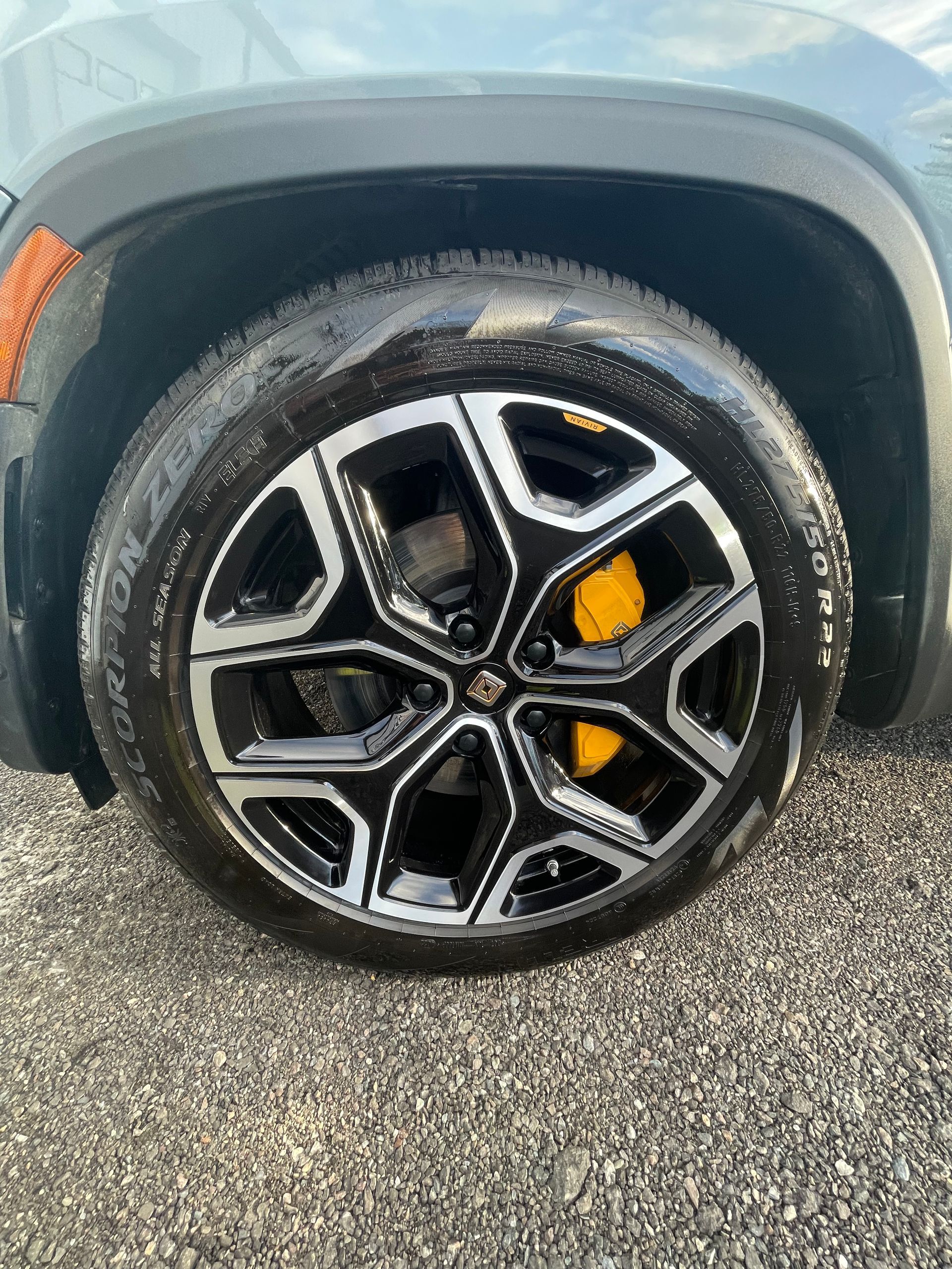 A close up of a car wheel on a gravel road.
