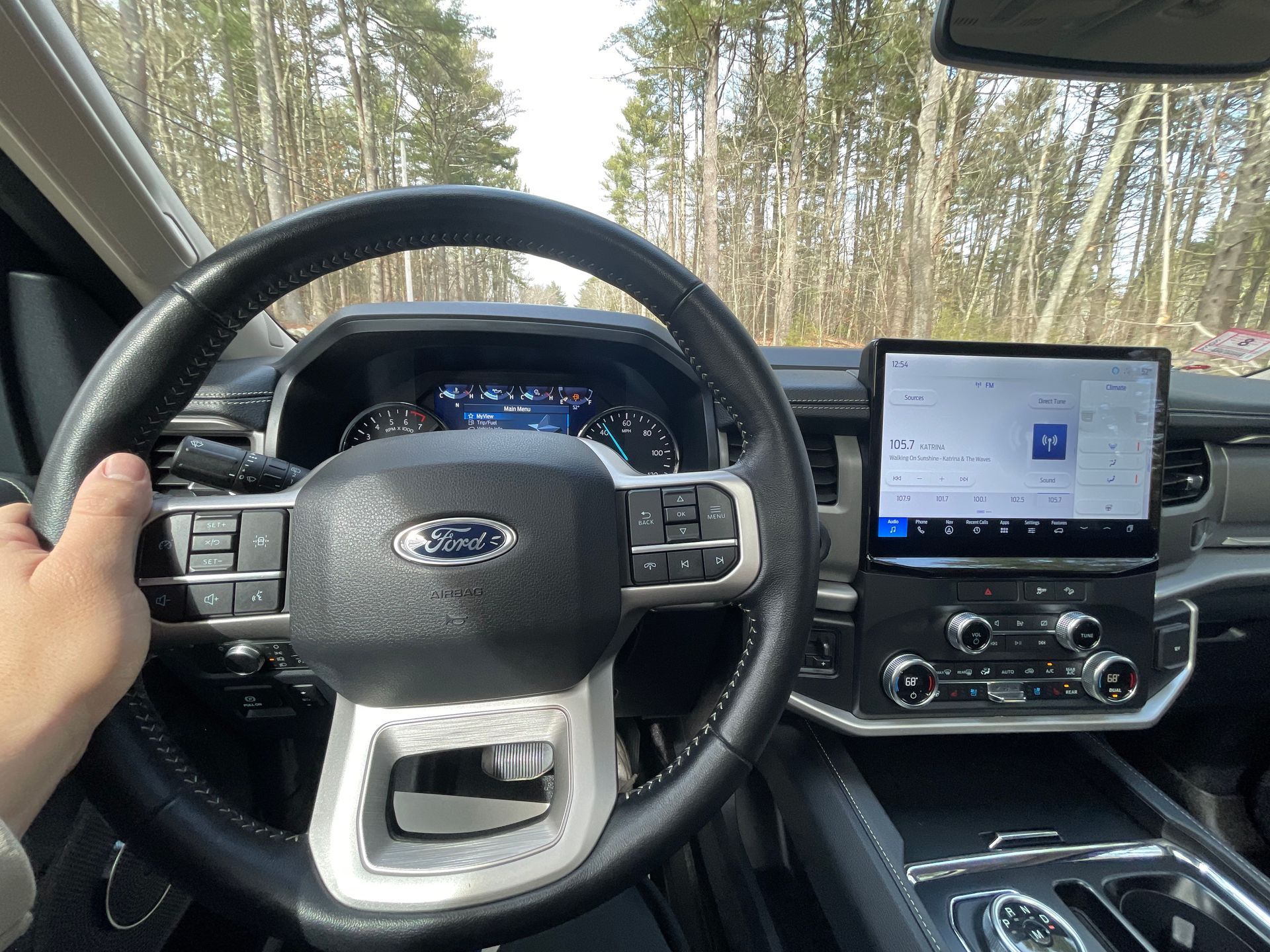 A person is driving a ford truck with a tablet mounted to the steering wheel.