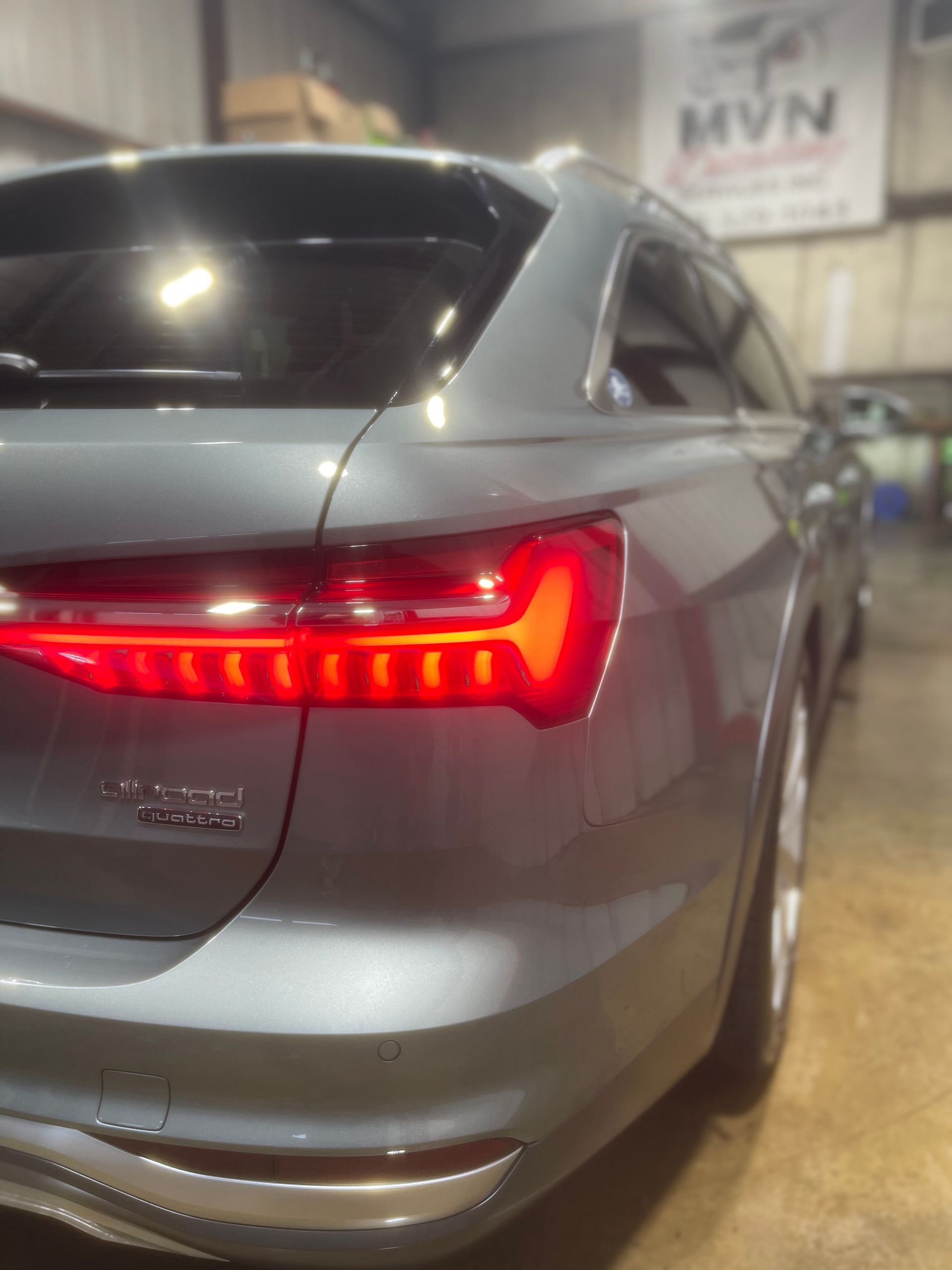 A gray car is parked in front of a sign that says mvn