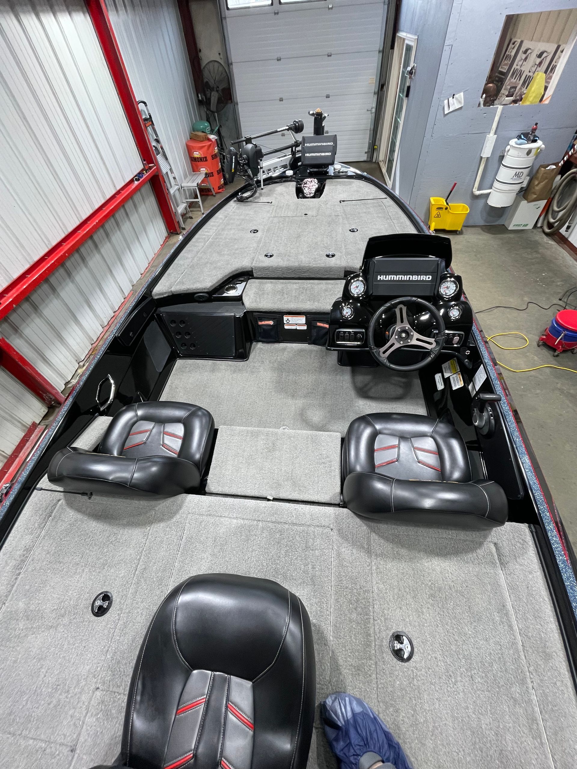 The inside of a fishing boat is shown from above in a garage.