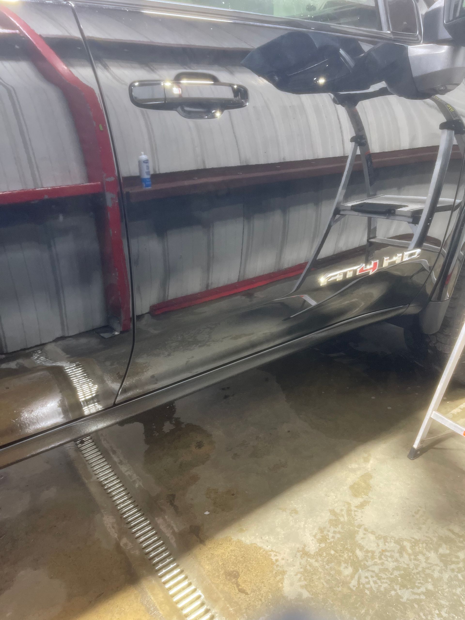 A car is sitting in a garage next to a ladder.