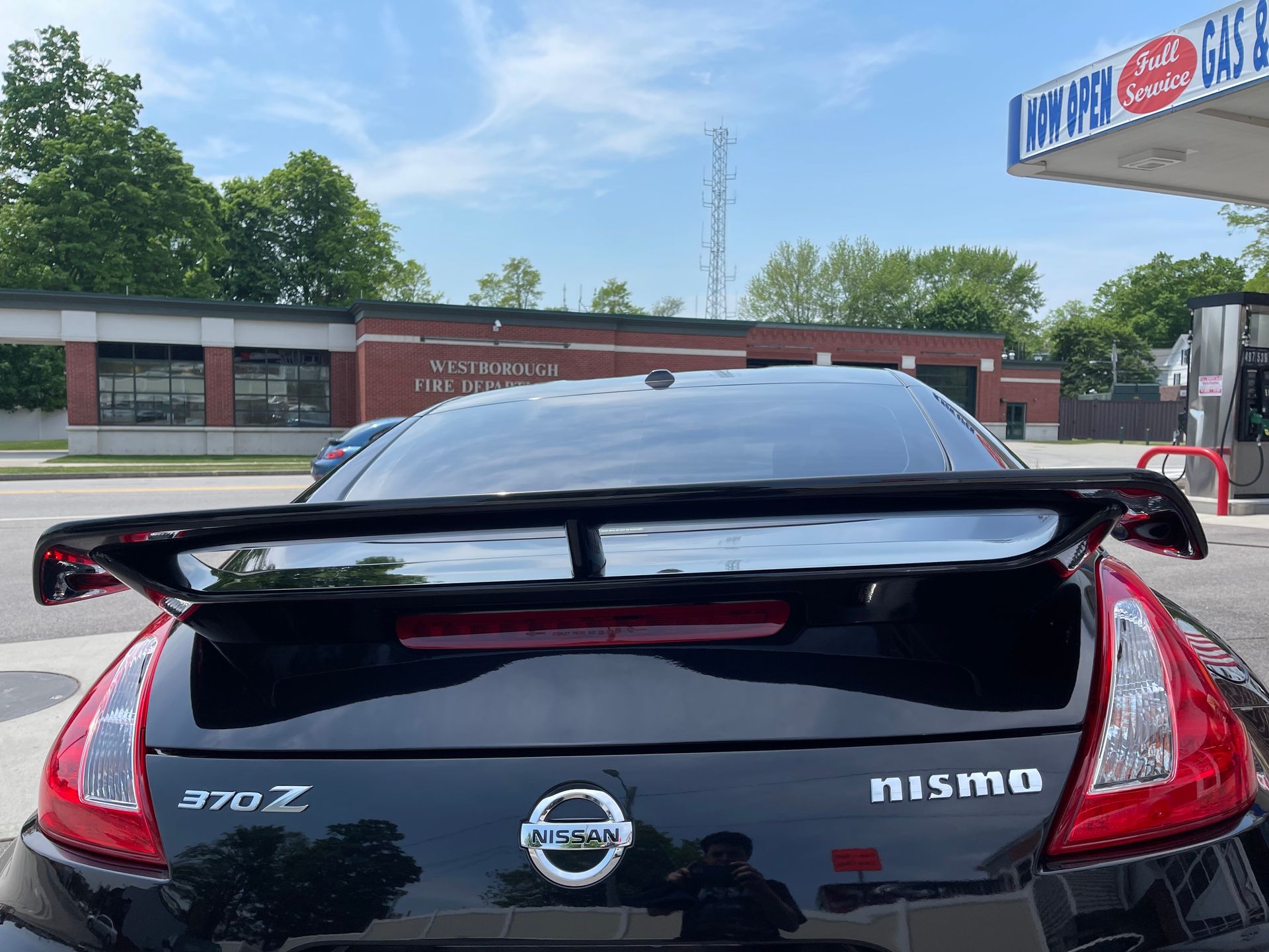 A black nissan nismo car is parked at a gas station.