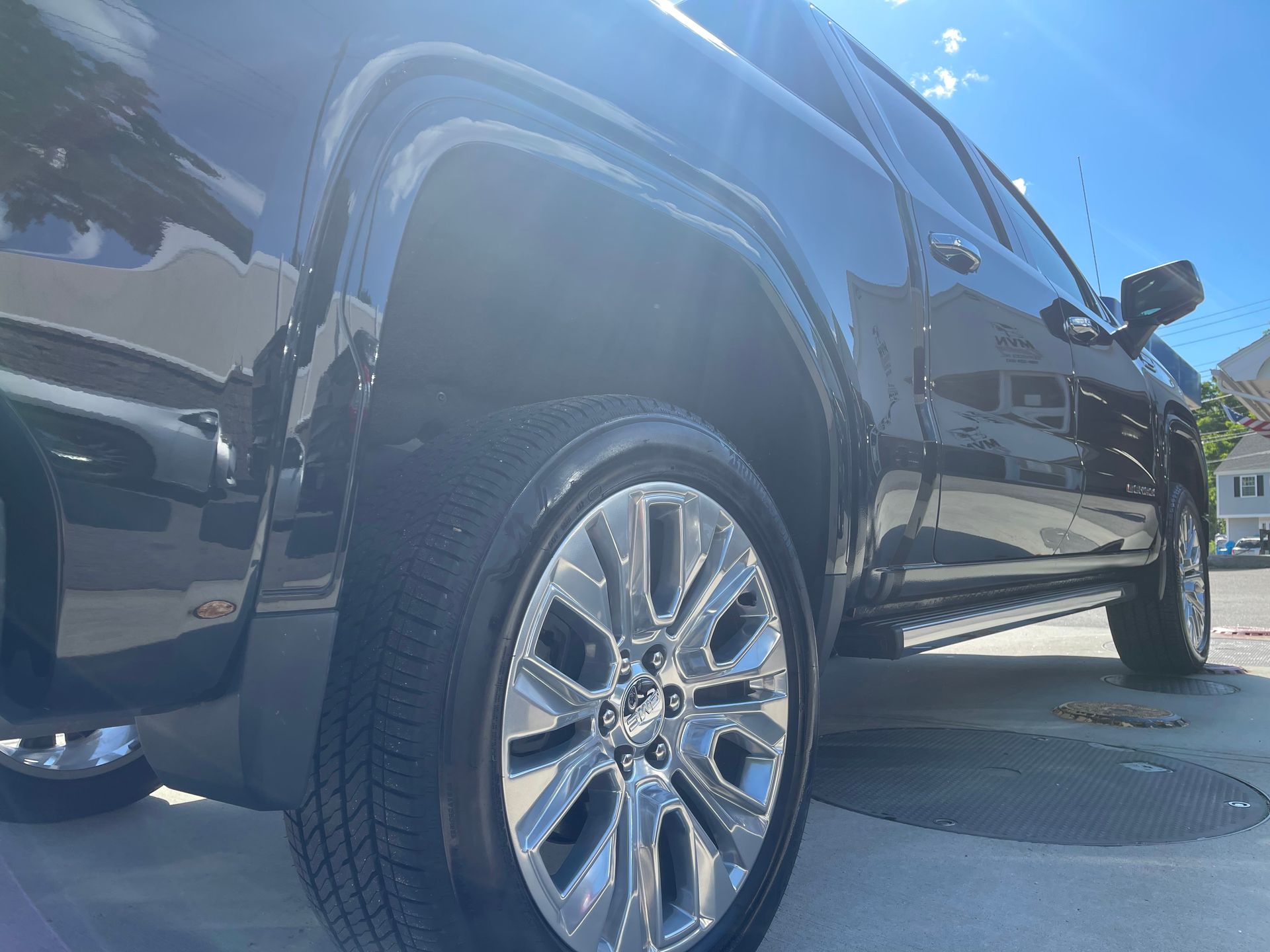 A black truck is parked in a driveway on a sunny day.