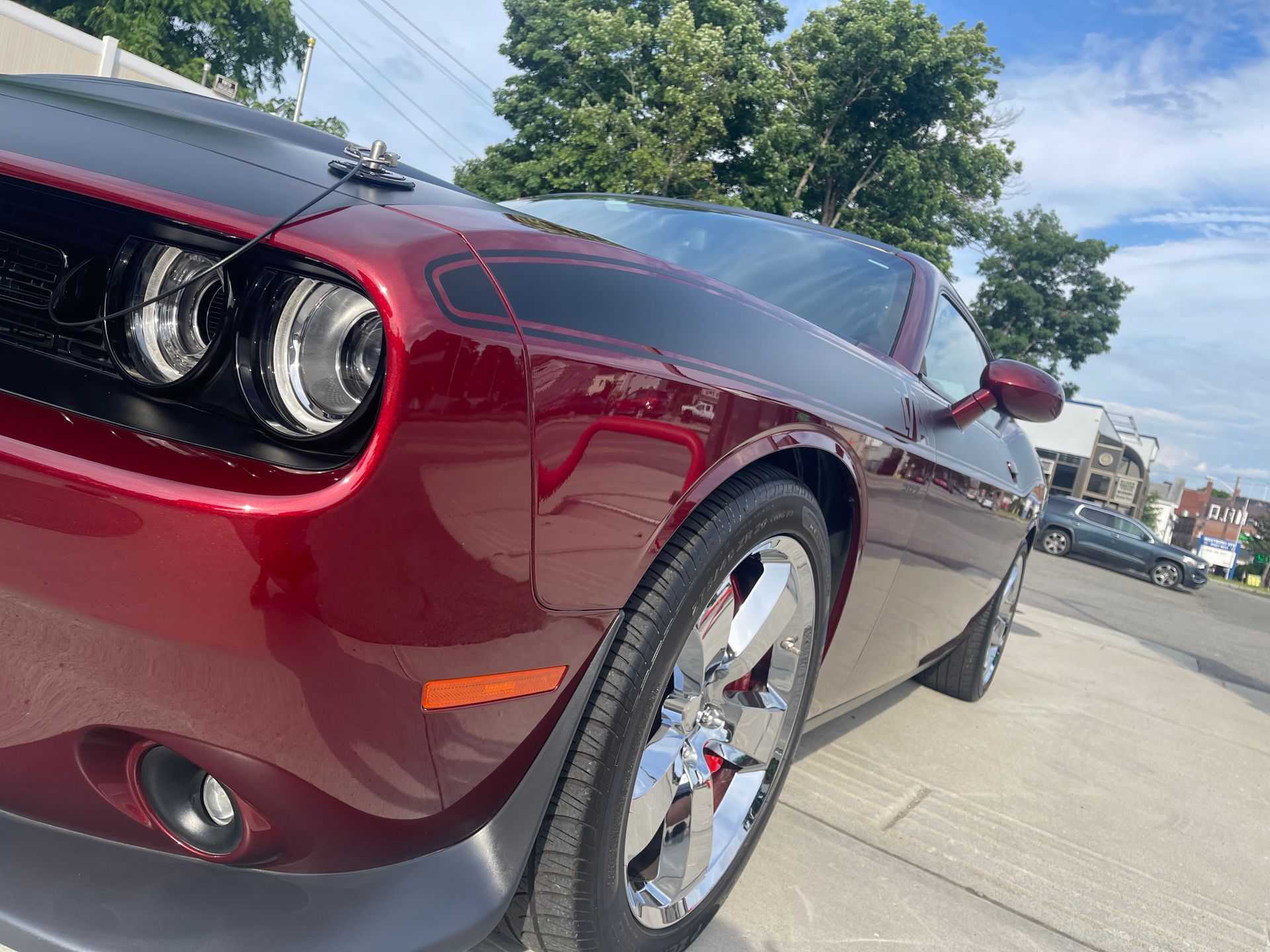 A red dodge challenger is parked on the side of the road.