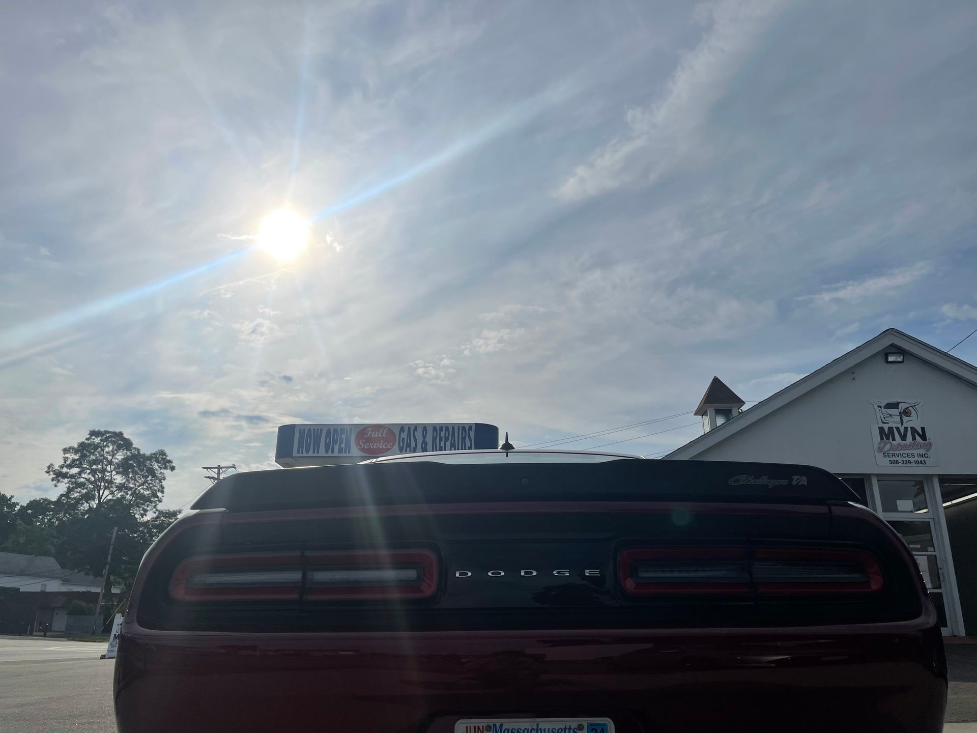 A red dodge challenger is parked in front of a white building.