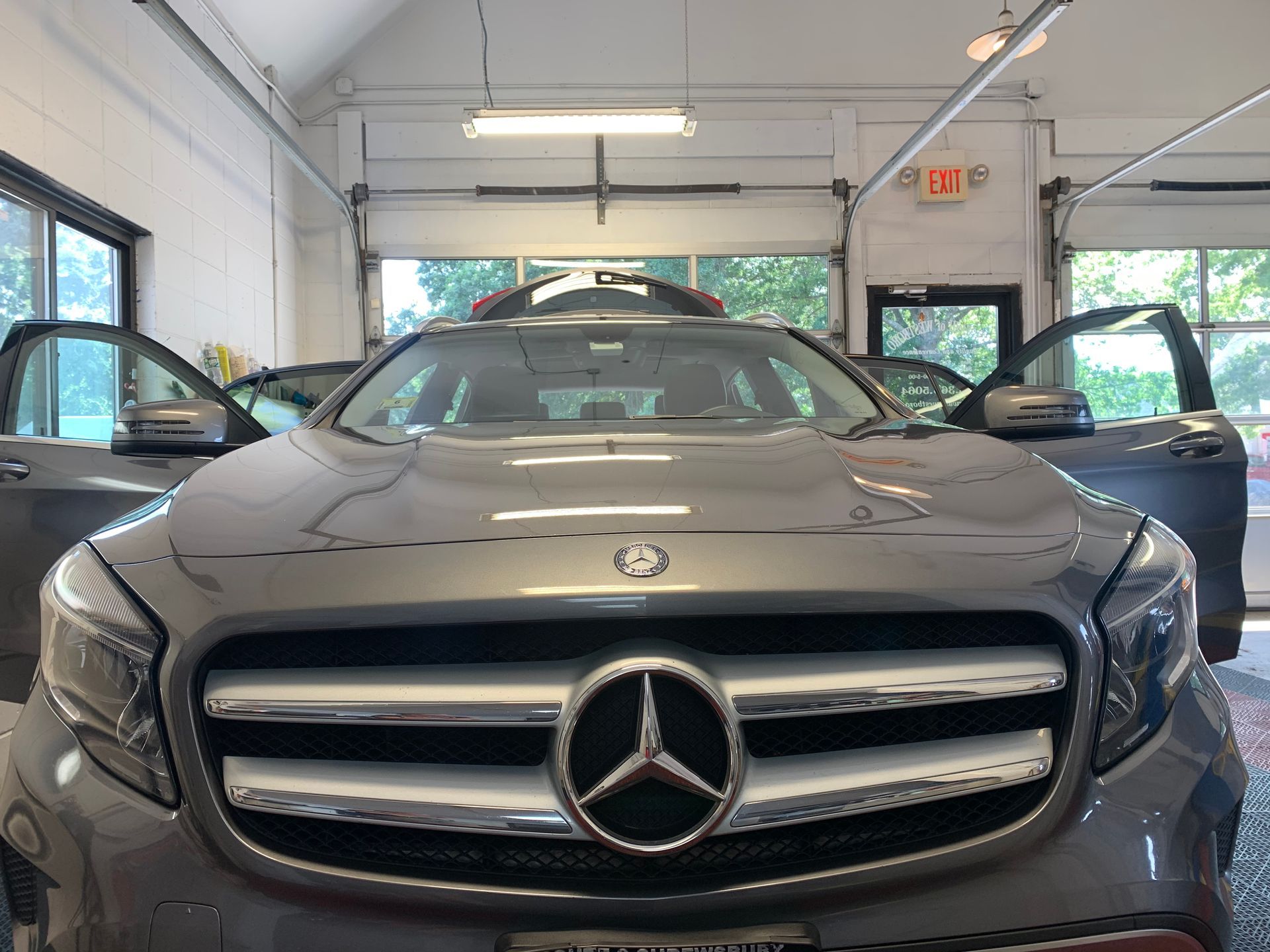 A mercedes benz is parked in a garage with its doors open.