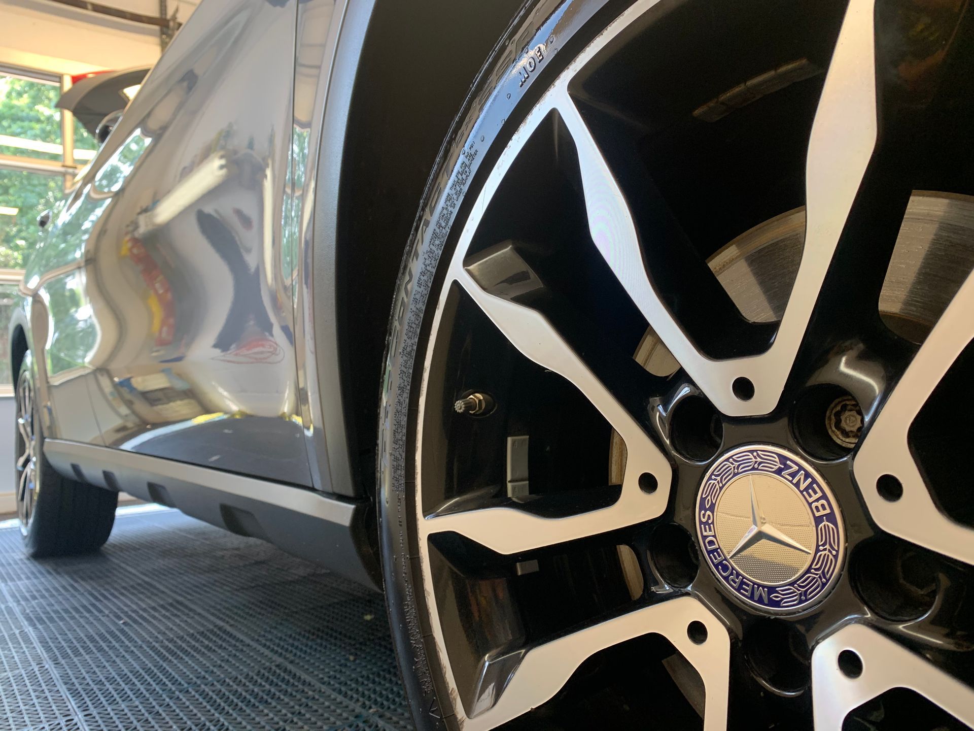 A close up of a mercedes wheel in a garage.