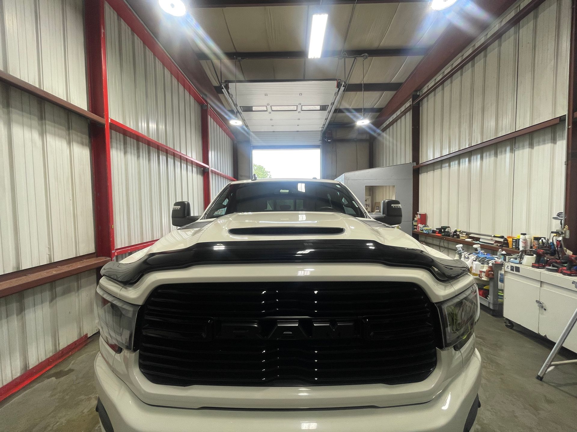 A white truck with a black grille is parked in a garage.