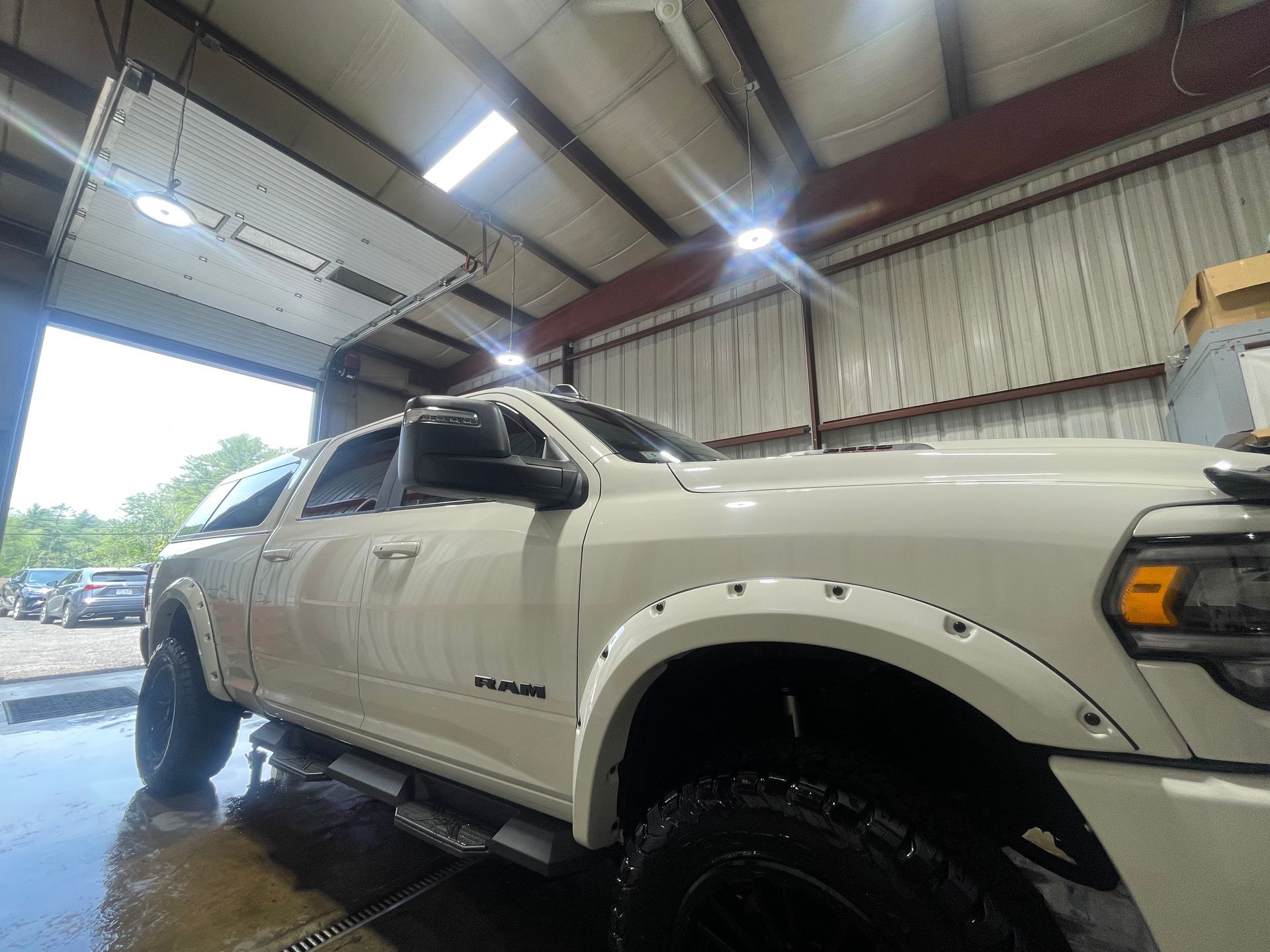 A white truck is parked in a garage with a garage door open.
