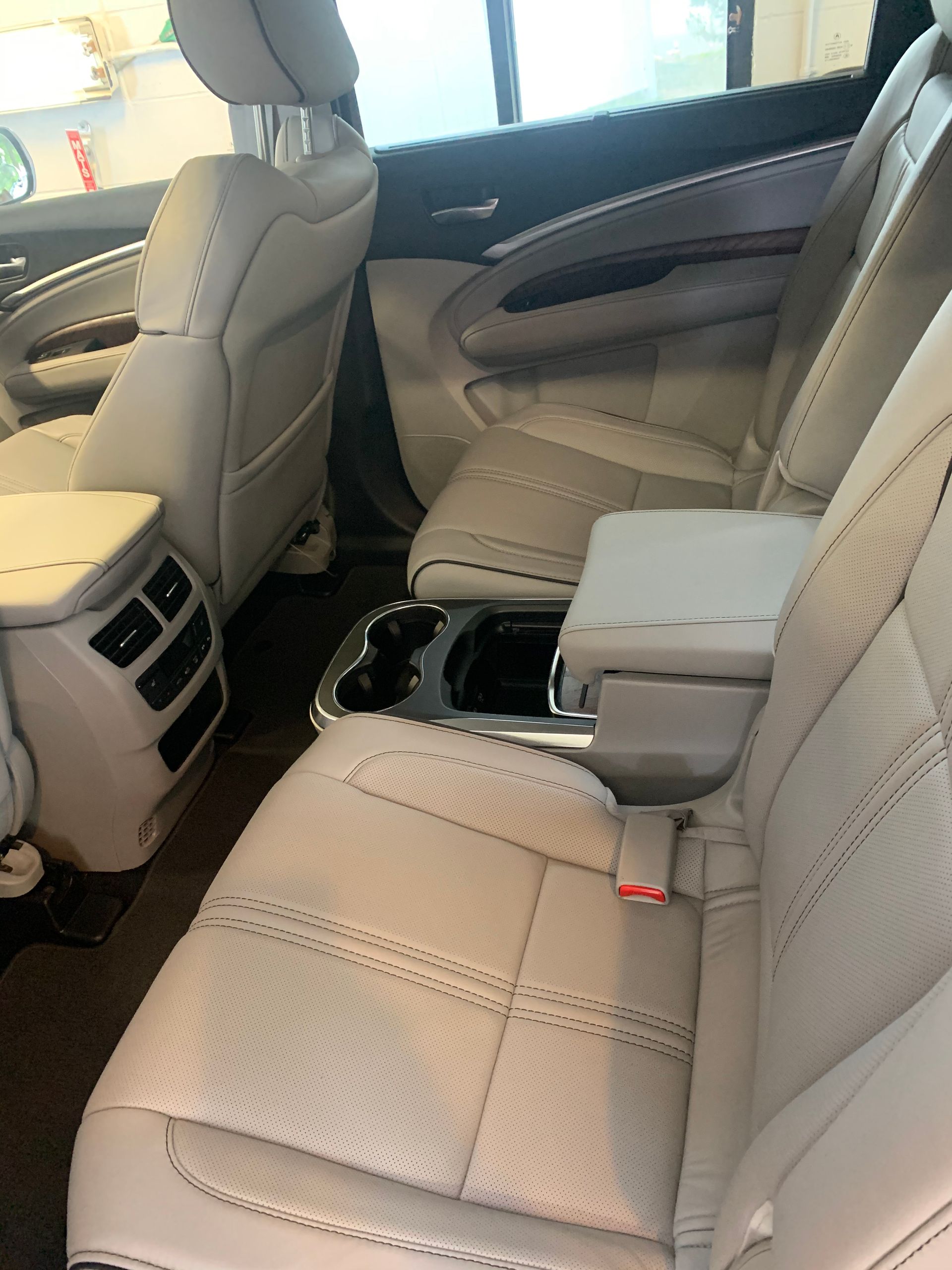 The back seat of a car with white leather seats.