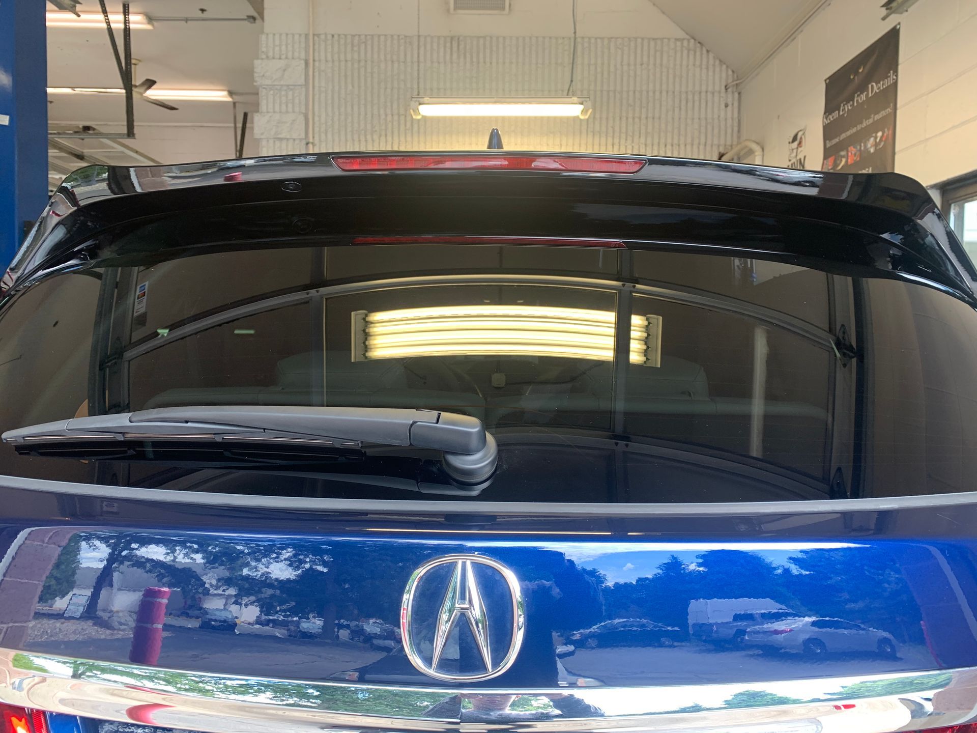 The back of a blue acura integra is shown in a garage.