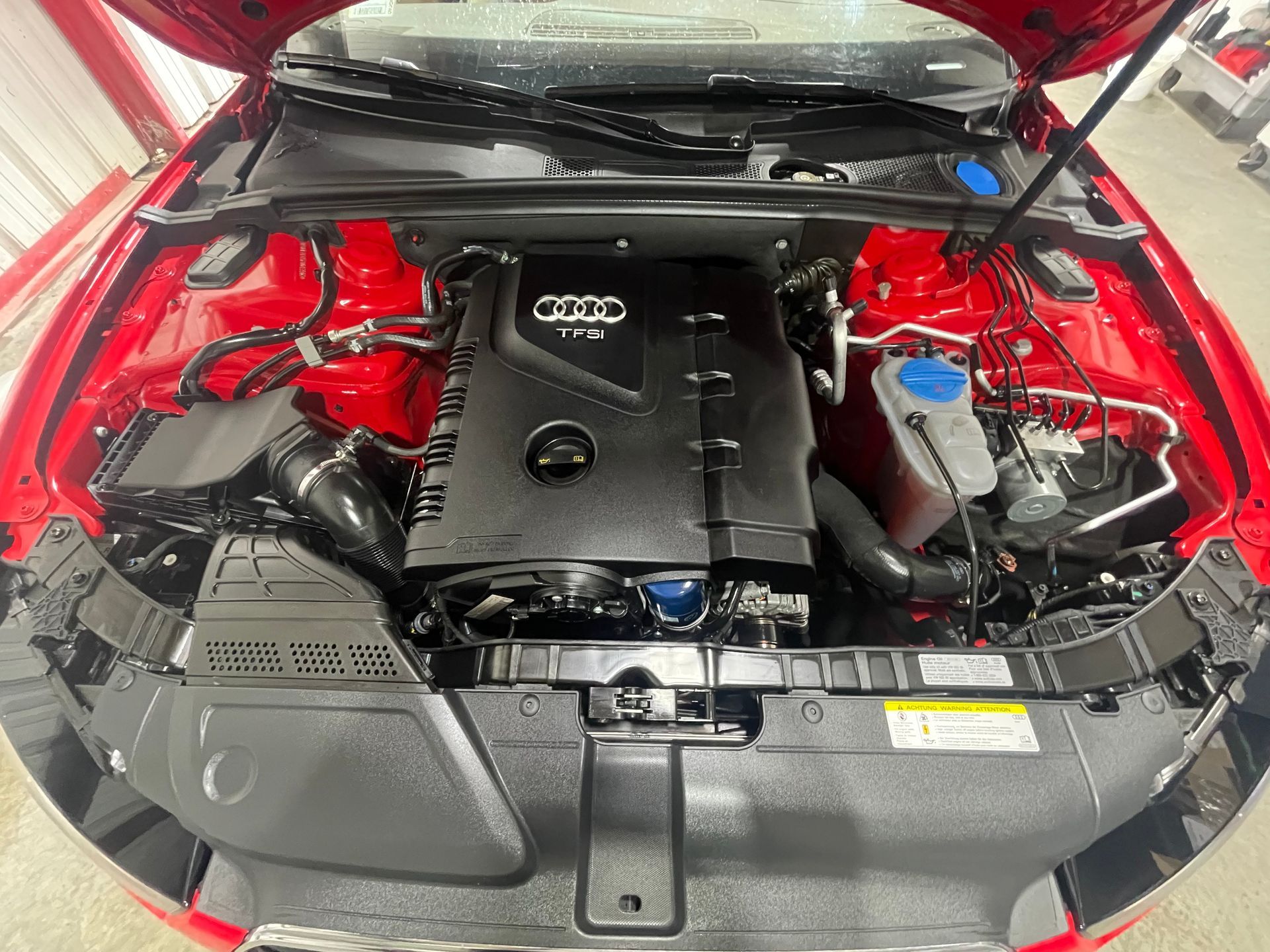The engine of a red audi q5 is shown with the hood up.
