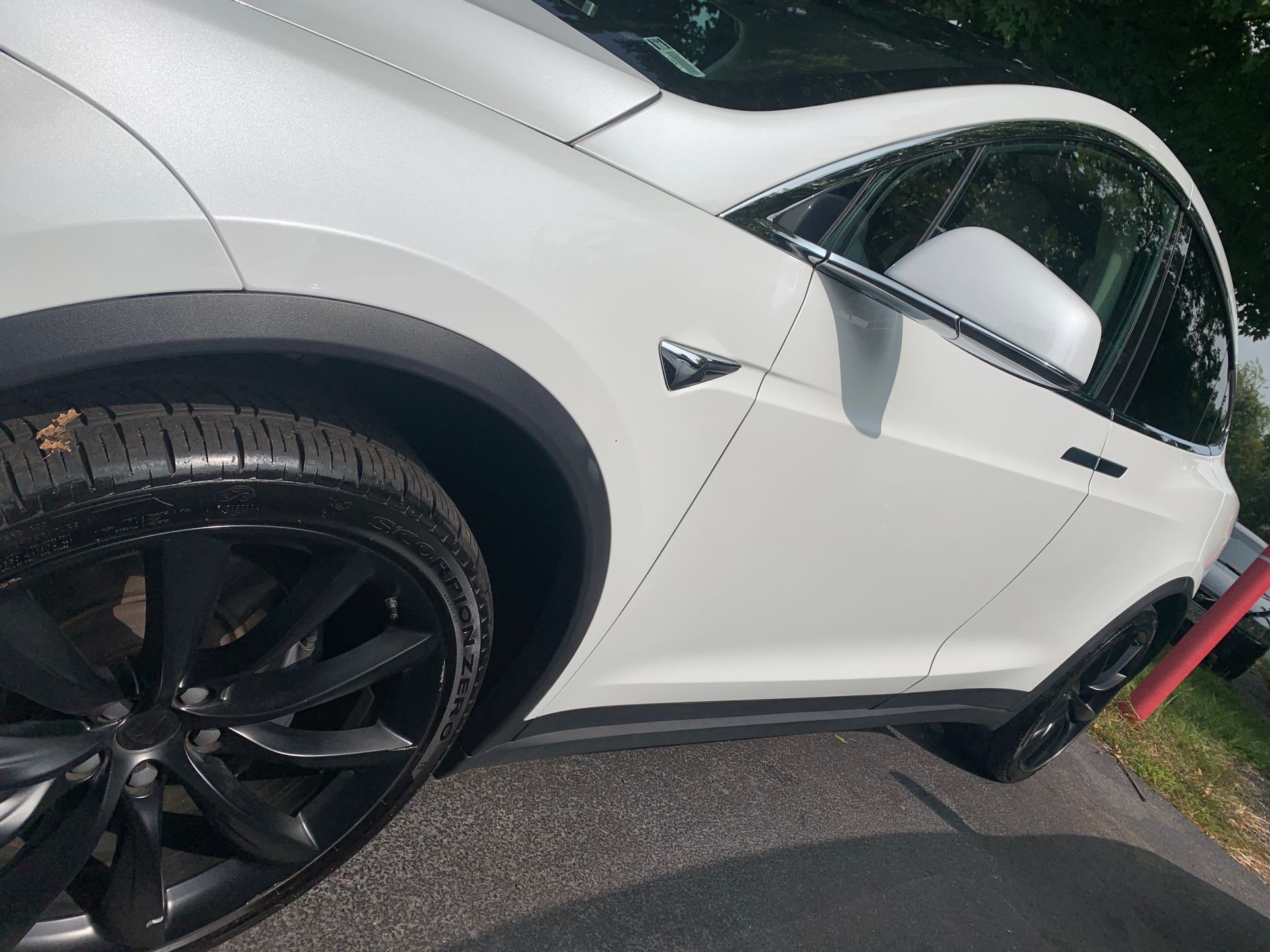 A white tesla model x is parked on the side of the road