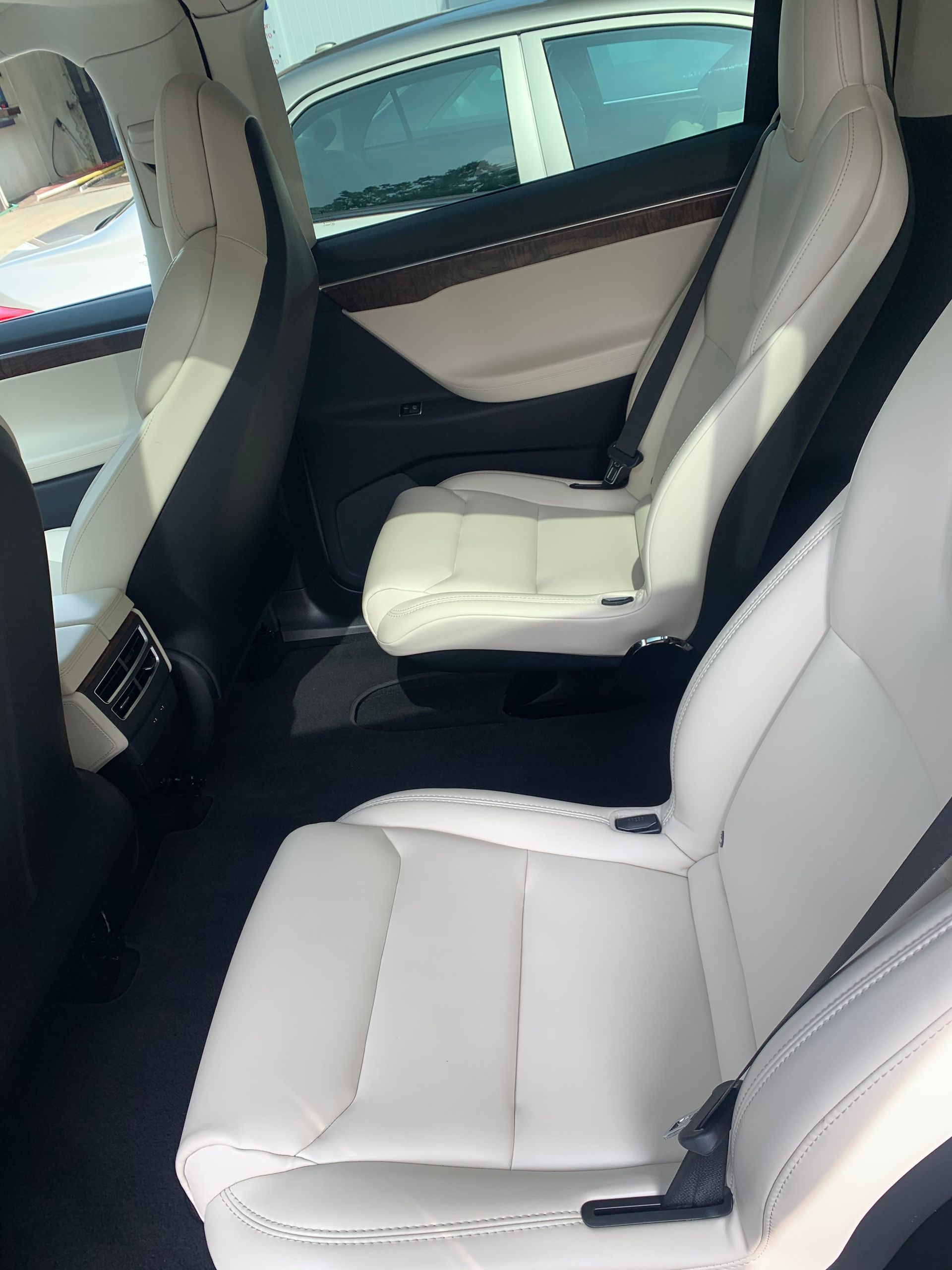The back seat of a tesla model x with white leather seats.