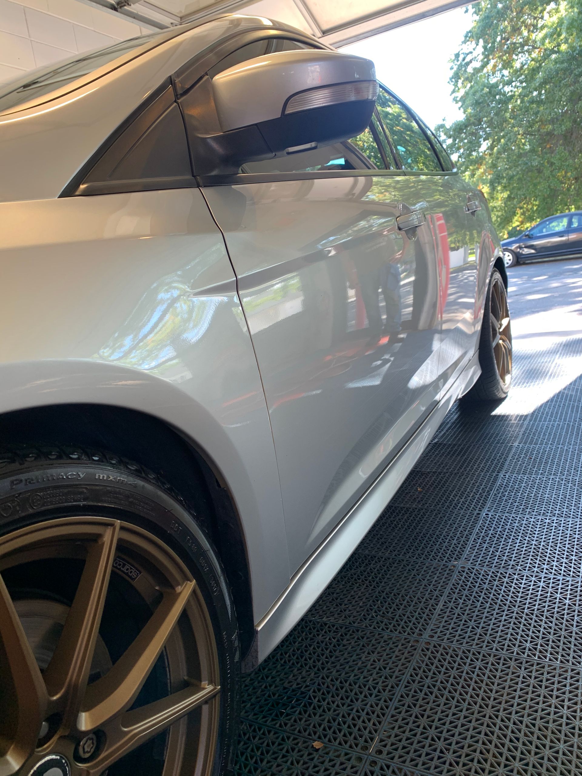 A silver car with gold wheels is parked in a garage.