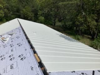 A white metal roof is being installed on a house.