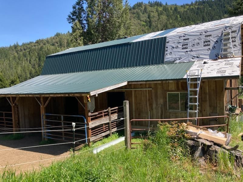 A barn with a green roof is being built in the mountains.
