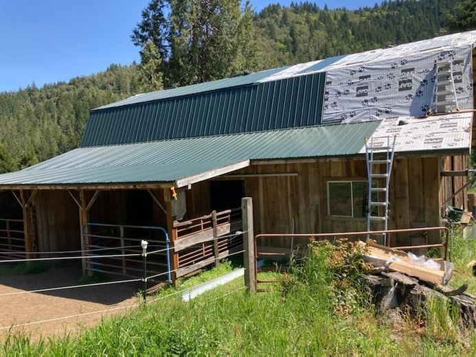 A barn with a green roof is being built in the mountains.