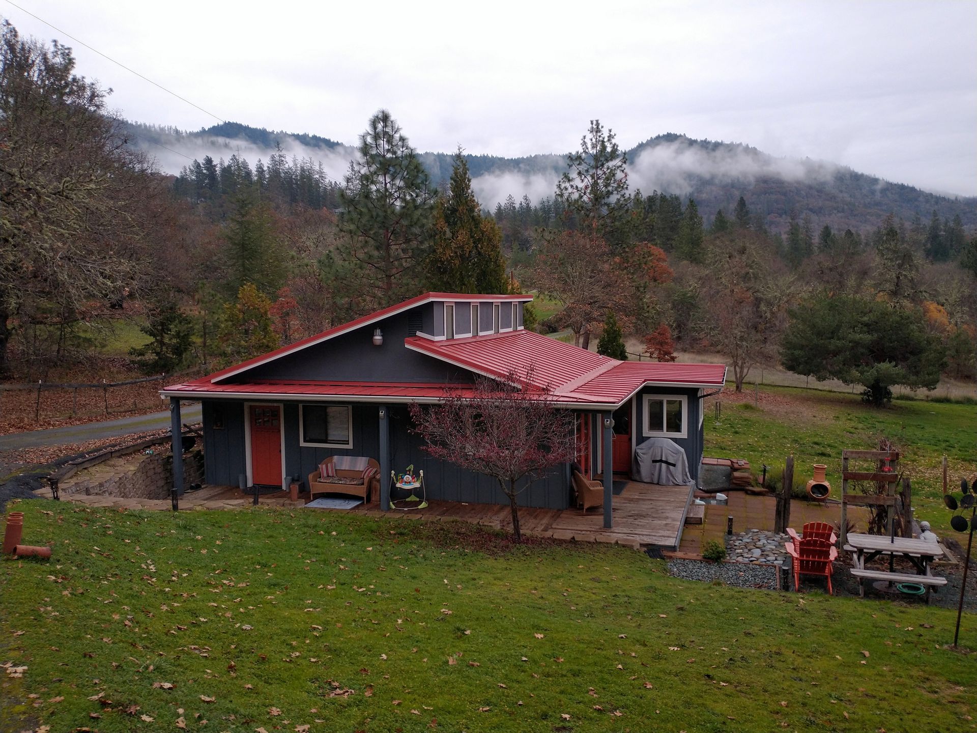 A house with a red roof is sitting in the middle of a grassy field.