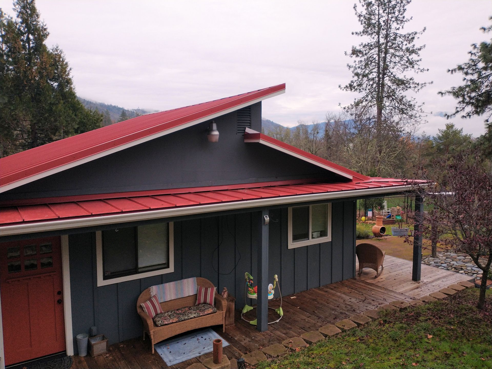 A gray house with a red roof and a porch